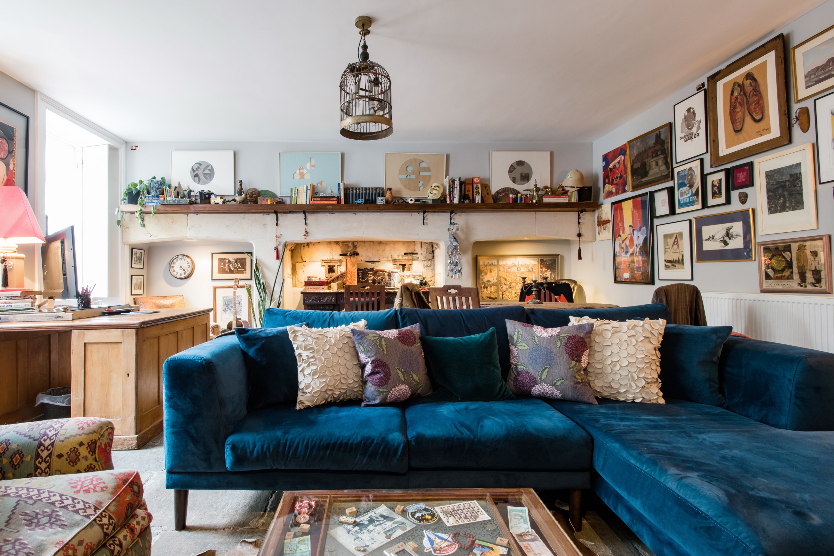 The living room of Maxwell's listing, with a large blue sofa and walls eclectically covered with framed images and artwork.