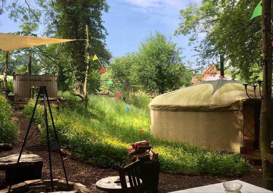 Emma's Off Grid Yurt surrounded by greenery, featuring a fire pit in the garden.