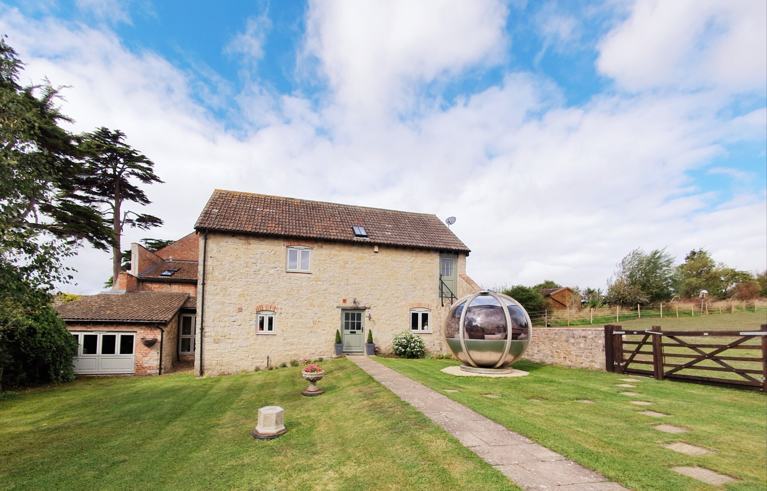 The cottage where the spare room is sutuated, surrounded by a large garden and a fireplace area.