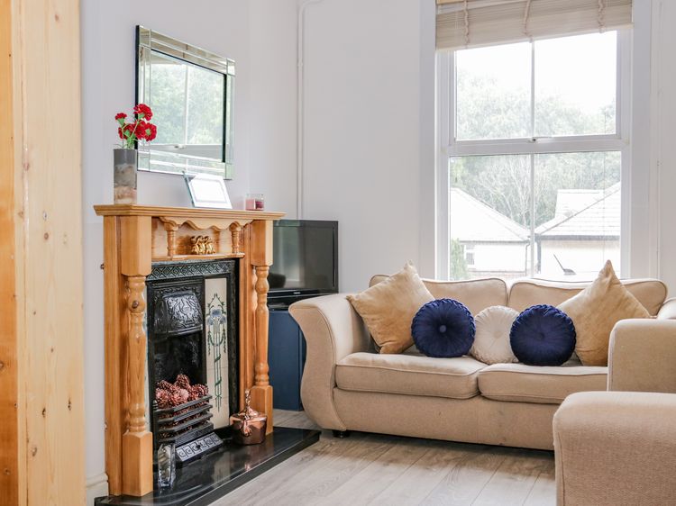 A image illustrating Rachael's cottage, showing a cosy, bright living room with a fireplace and comfortable sofas where family and friends can gather. 