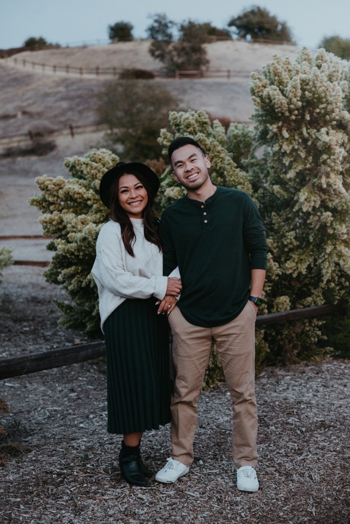 A young couple arm in arm smiling and standing in the desert