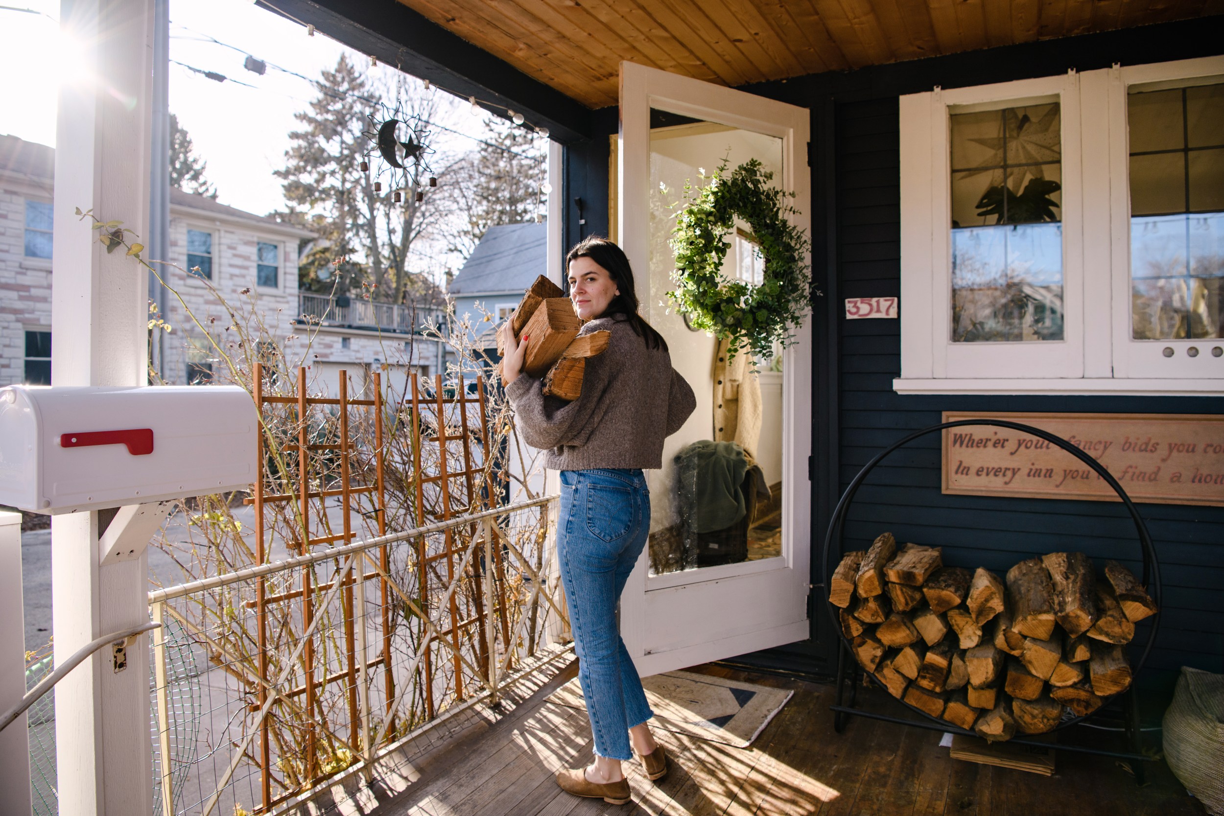 Samanta, a Host, holds an armful of chopped wood and is headed into her Airbnb.
