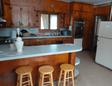 A photo of the old Filomena kitchen with all wood cabinets and dated appliances.