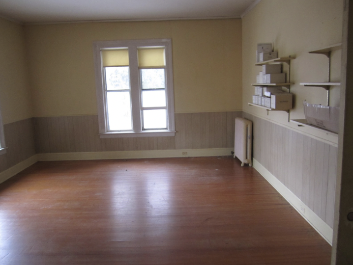 Empty room with a wood floor and pale yellow walls – a few floating shelving units on one wall to the right.