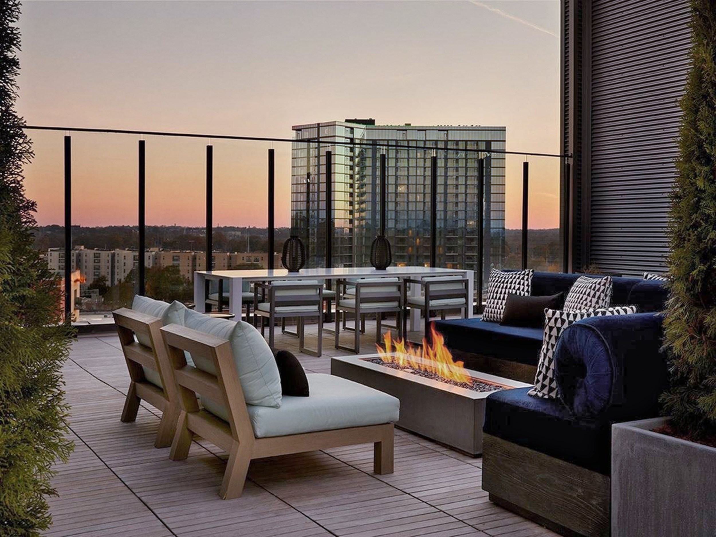 Apartment rooftop deck with seating around a fire pit and a view of a big building in the distance.