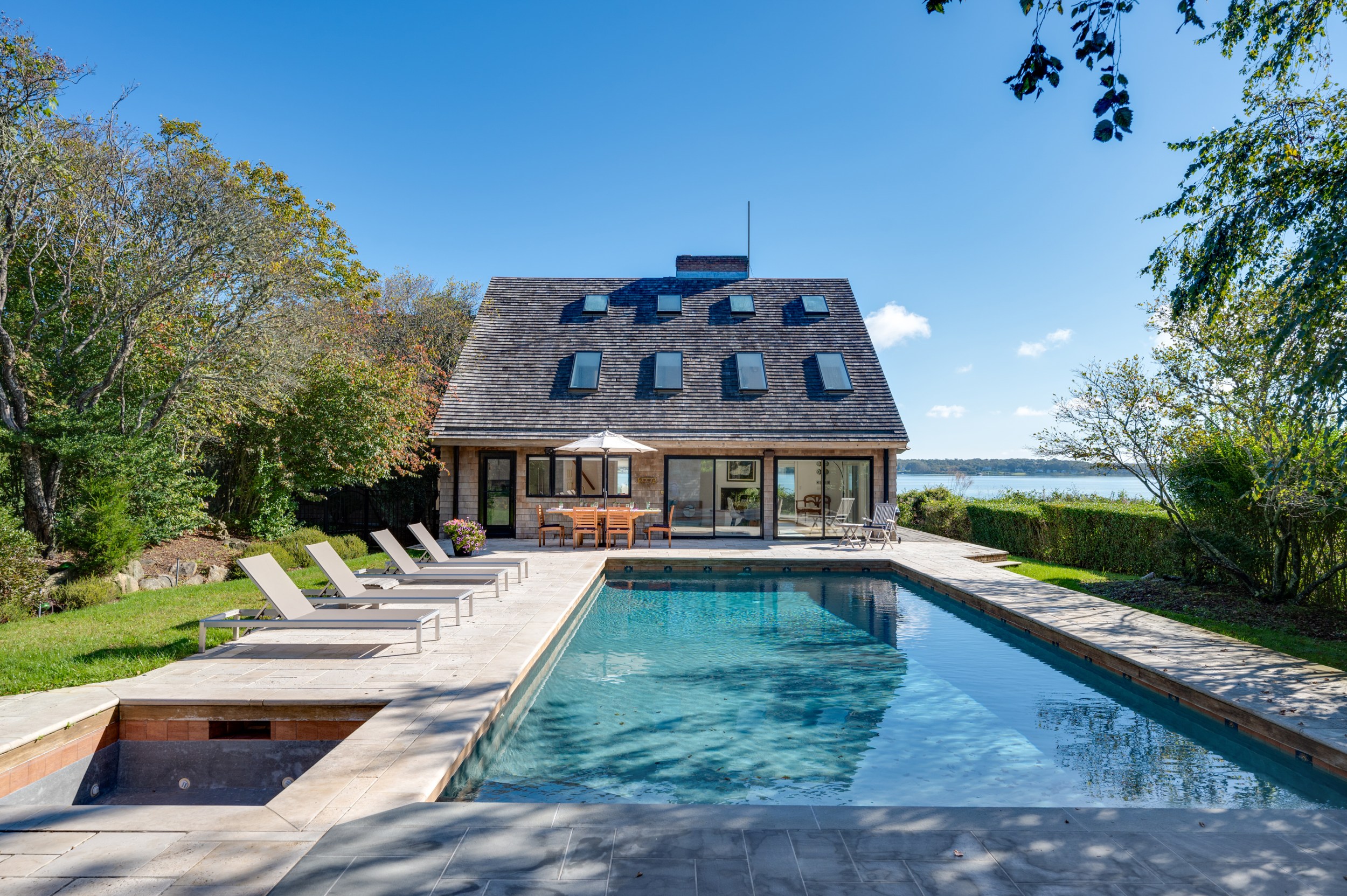 Outside view of a home near a lake with solar panels, a pool, and a jacuzzi