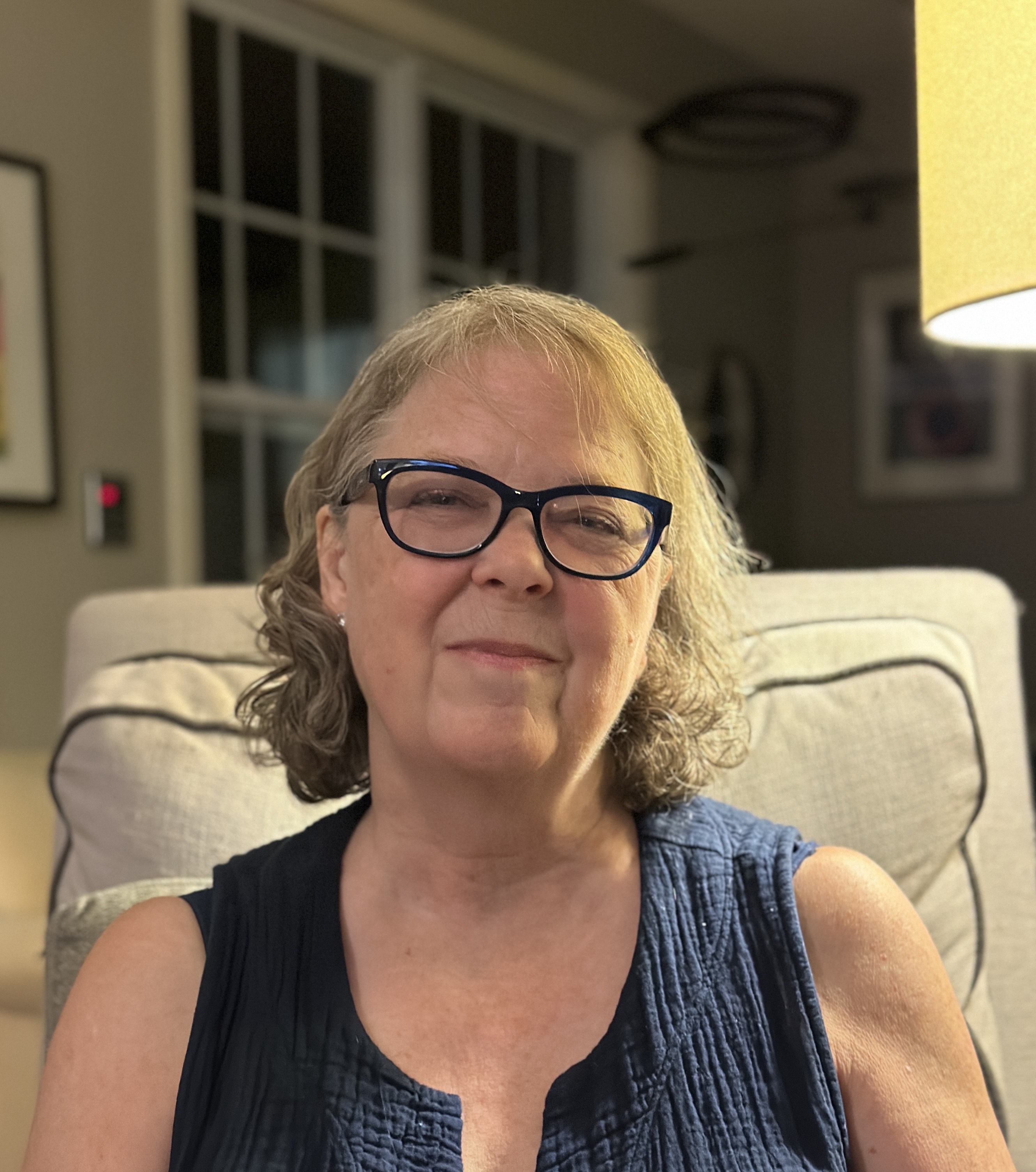 Woman sitting on couch and smiling for a photo.