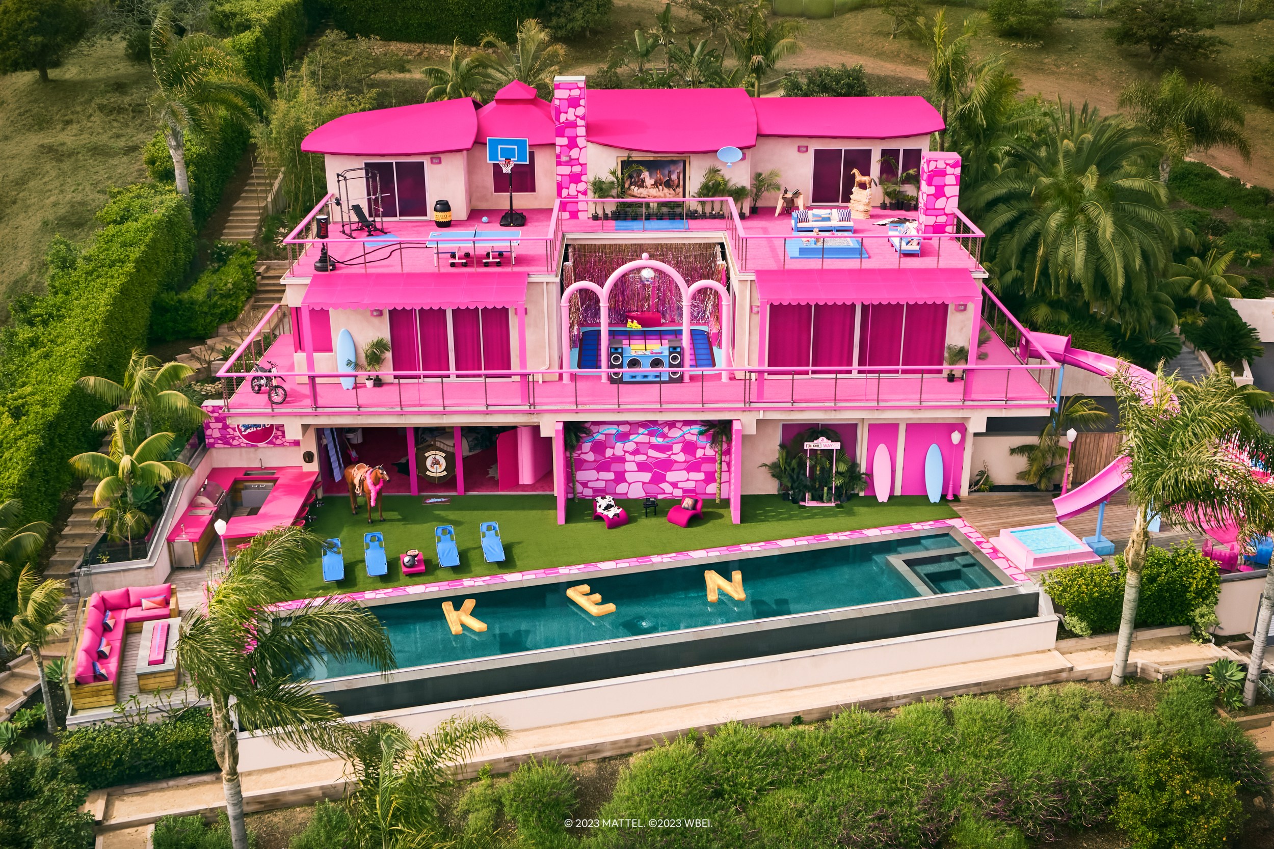 Exterior of Ken's Dreamhouse, three stories high with a huge rectangular pool in the backyard, surrounded by Malibu foliage.