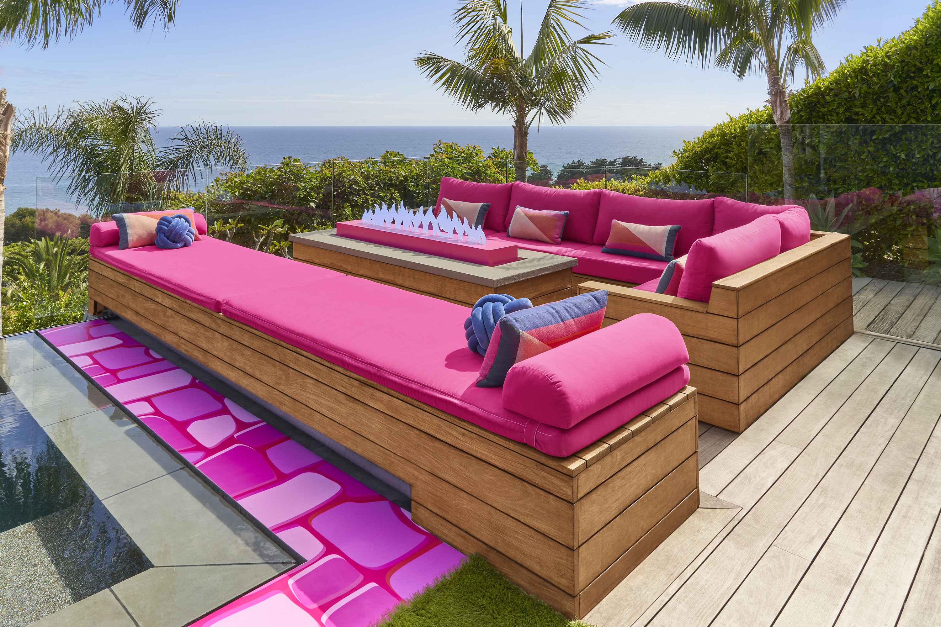 Two outdoor benches with pink cushions and fluffly pillows, with a Barbie-staged fireplace in the center.