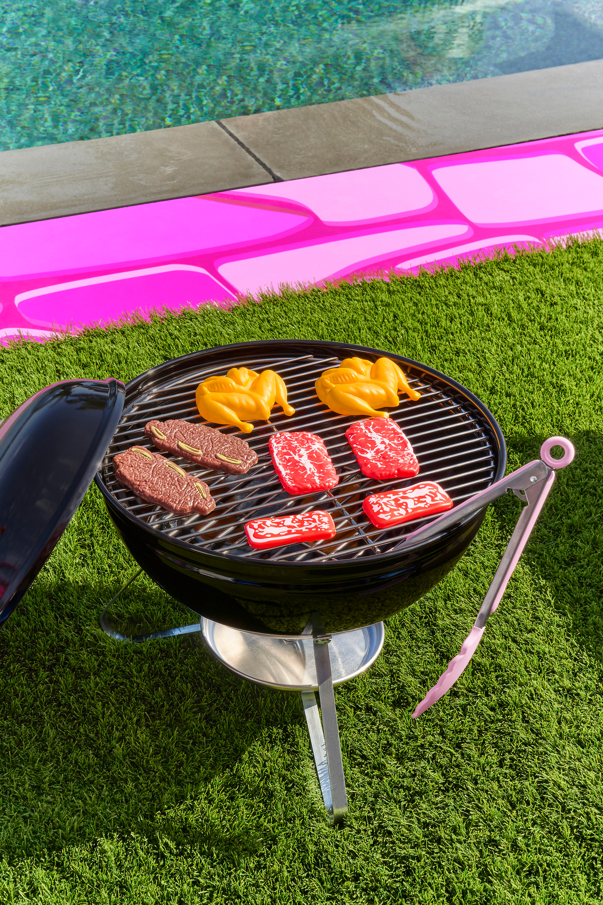 Outdoor grill open by the pool with various meats cooking up.