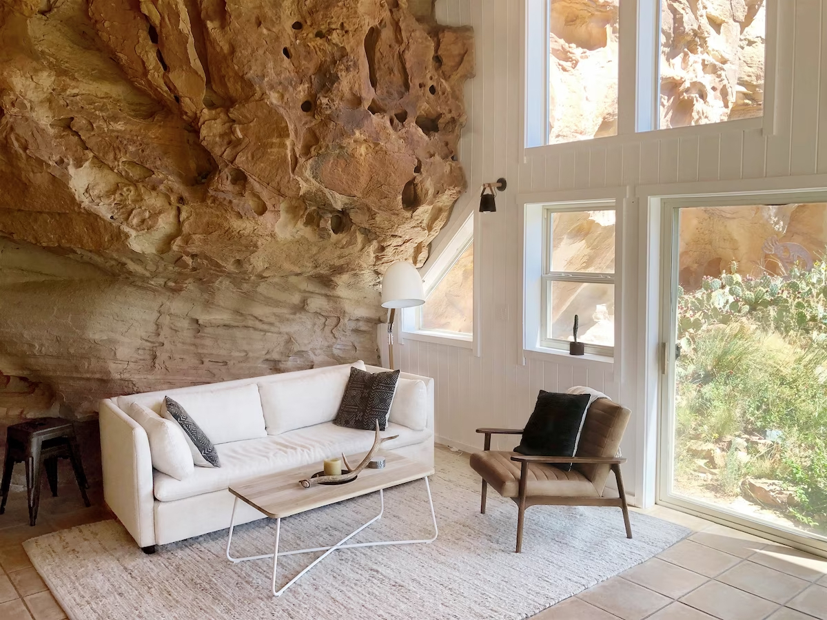 Sofa with an armchair and coffee table with a decorative rock wall in the background. 