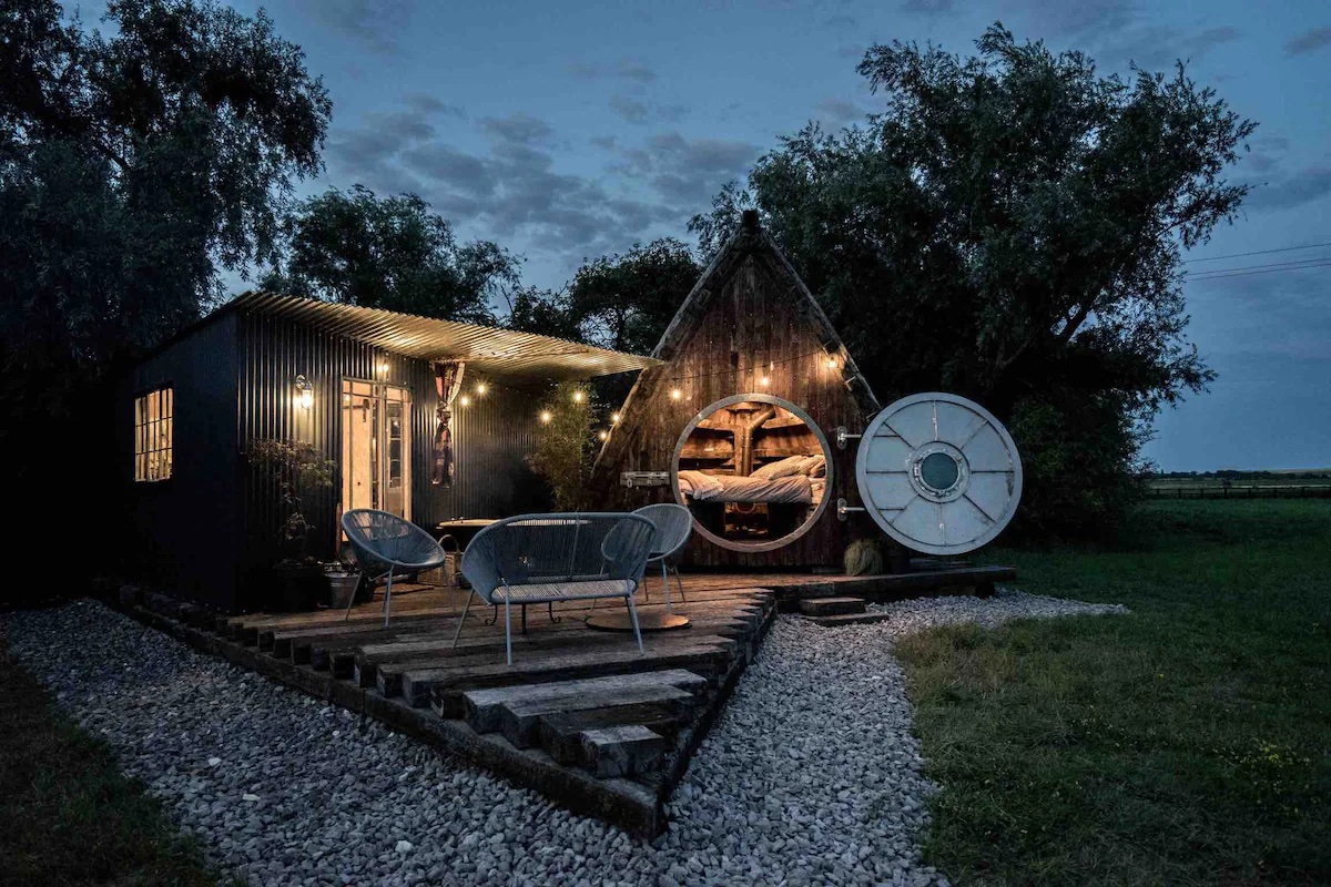 Unique camping set up with a timber a frame cabin and outdoor furniture in the front. 