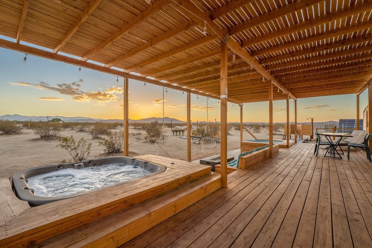 An outdoor area with a spa and Joshua Tree in the background. 