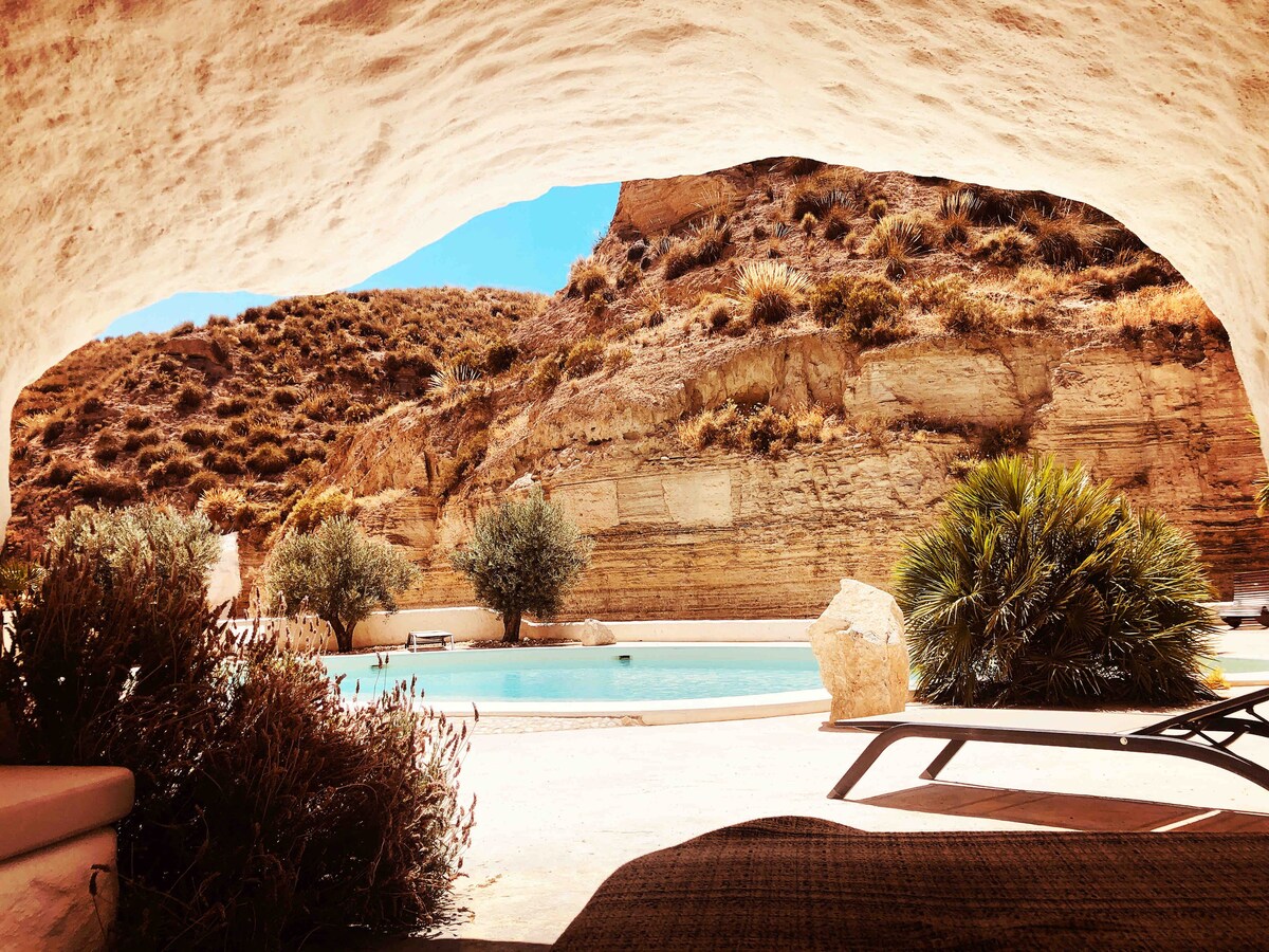 A picture of an outdoor area with a pool surrounded by rocky mountains. 