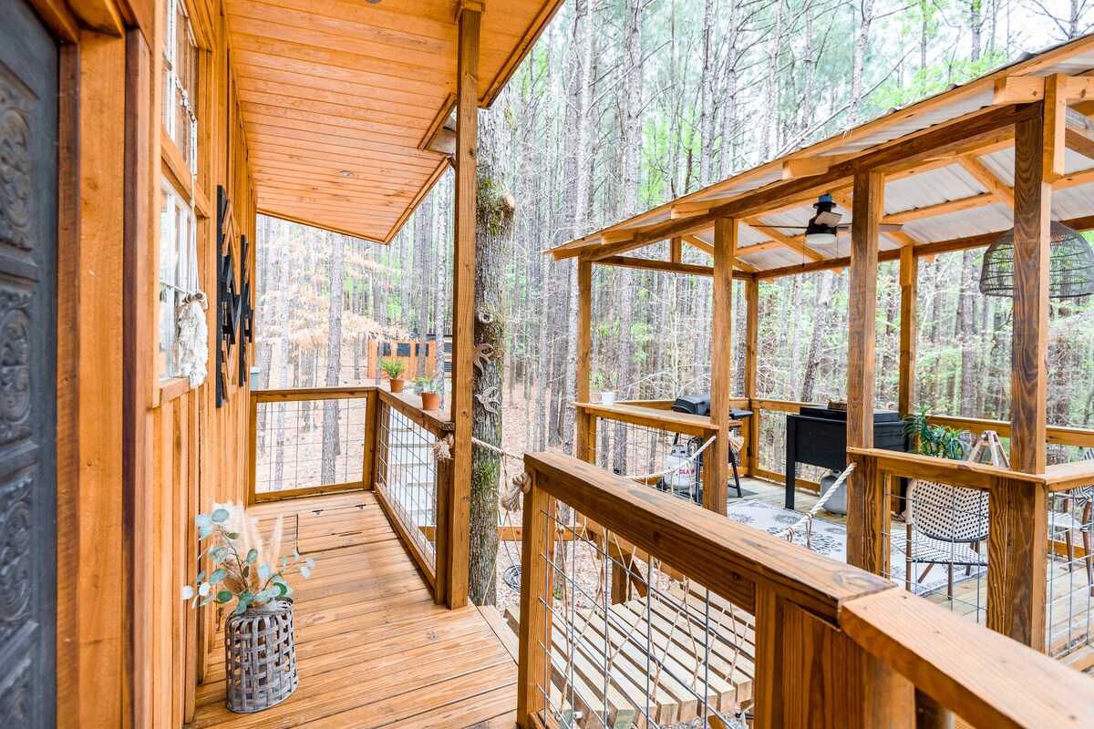 A wooden decking with a sitting area and a forest in the background. 