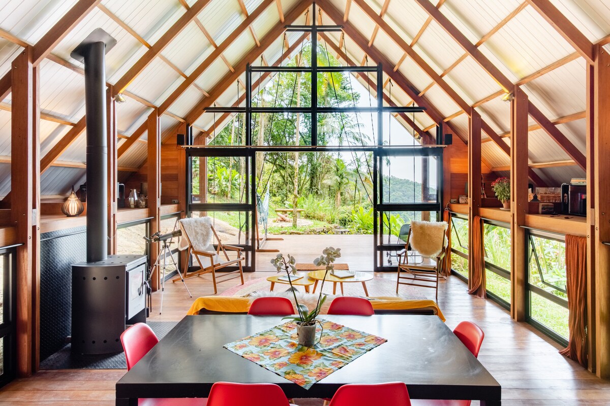 Dining room setting with an a-frame view of a rainforest in the backdrop