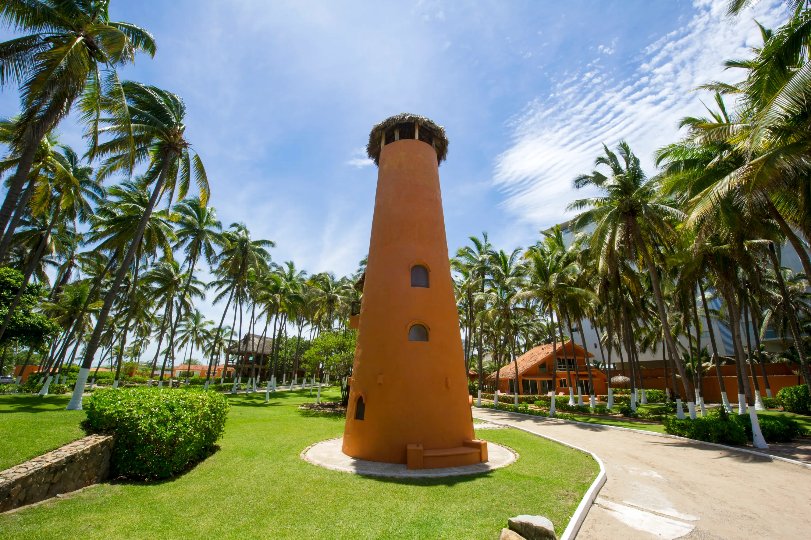 A clay faro surrounded by palm trees.
