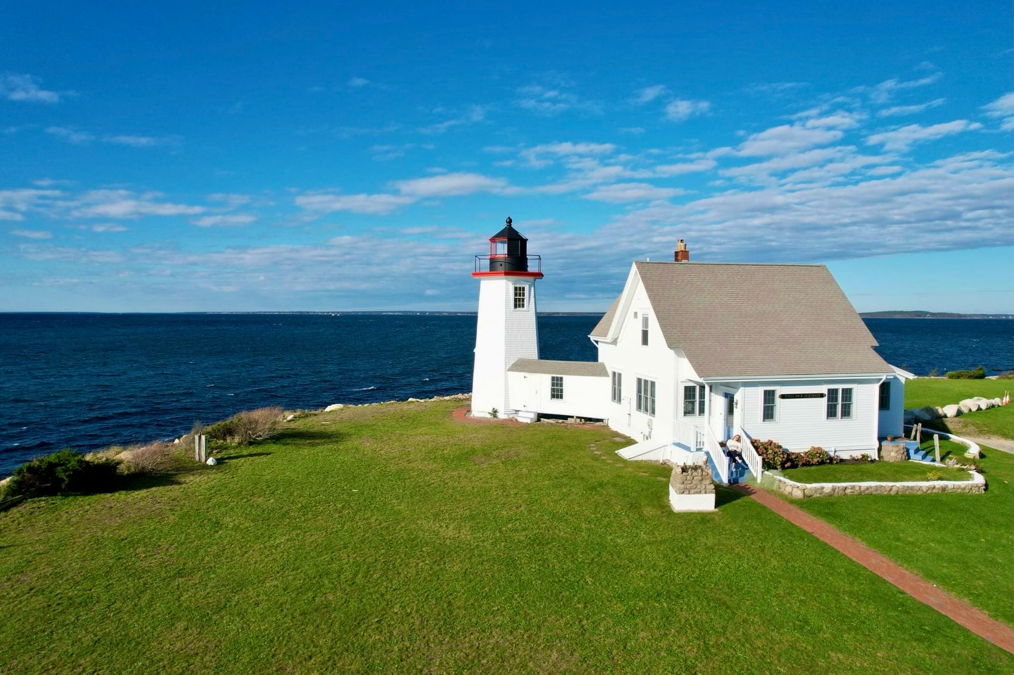 A lighthouse and lighthouse keeper's house on a grassy field during the day.