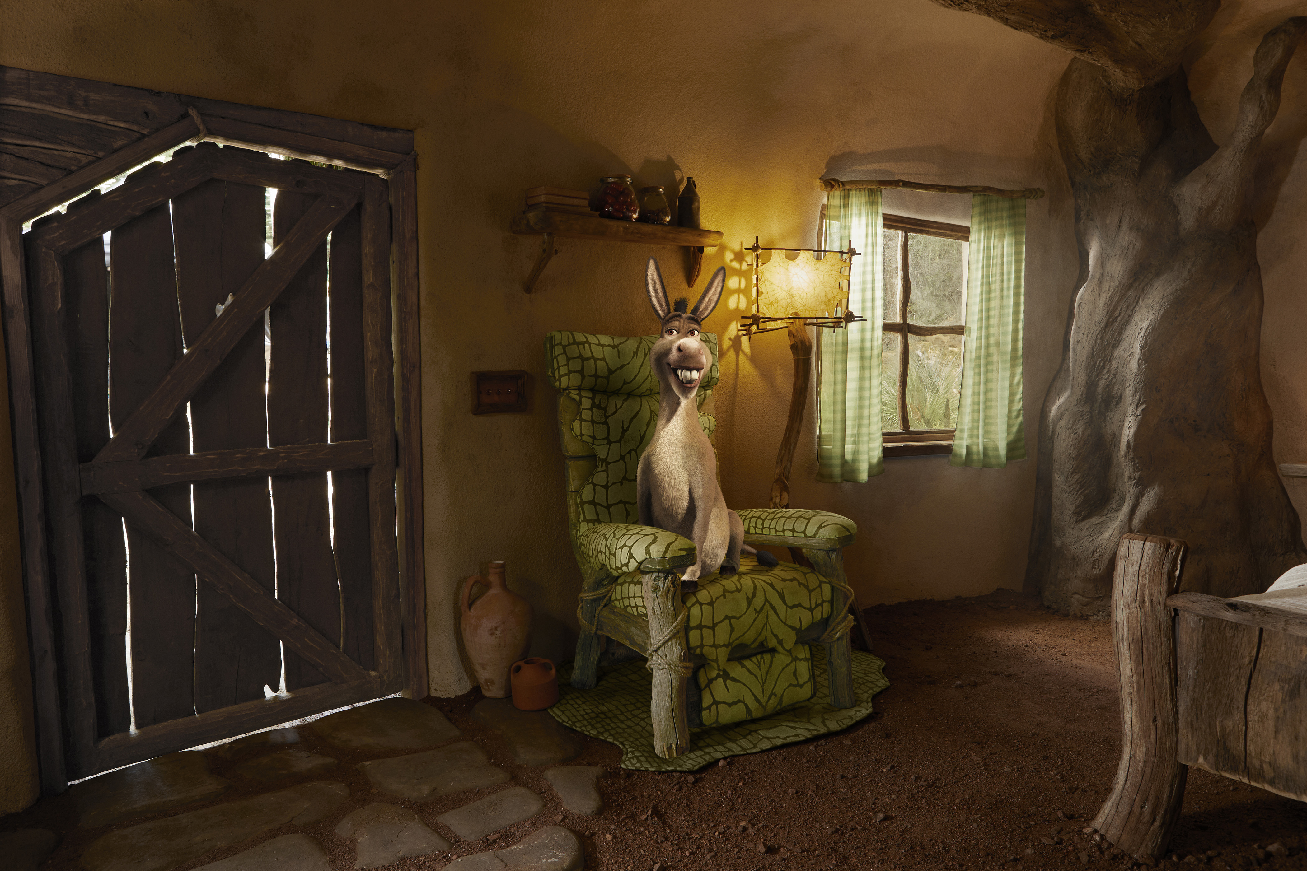 A smiling Donkey seated on an armchair inside Shrek's Swamp