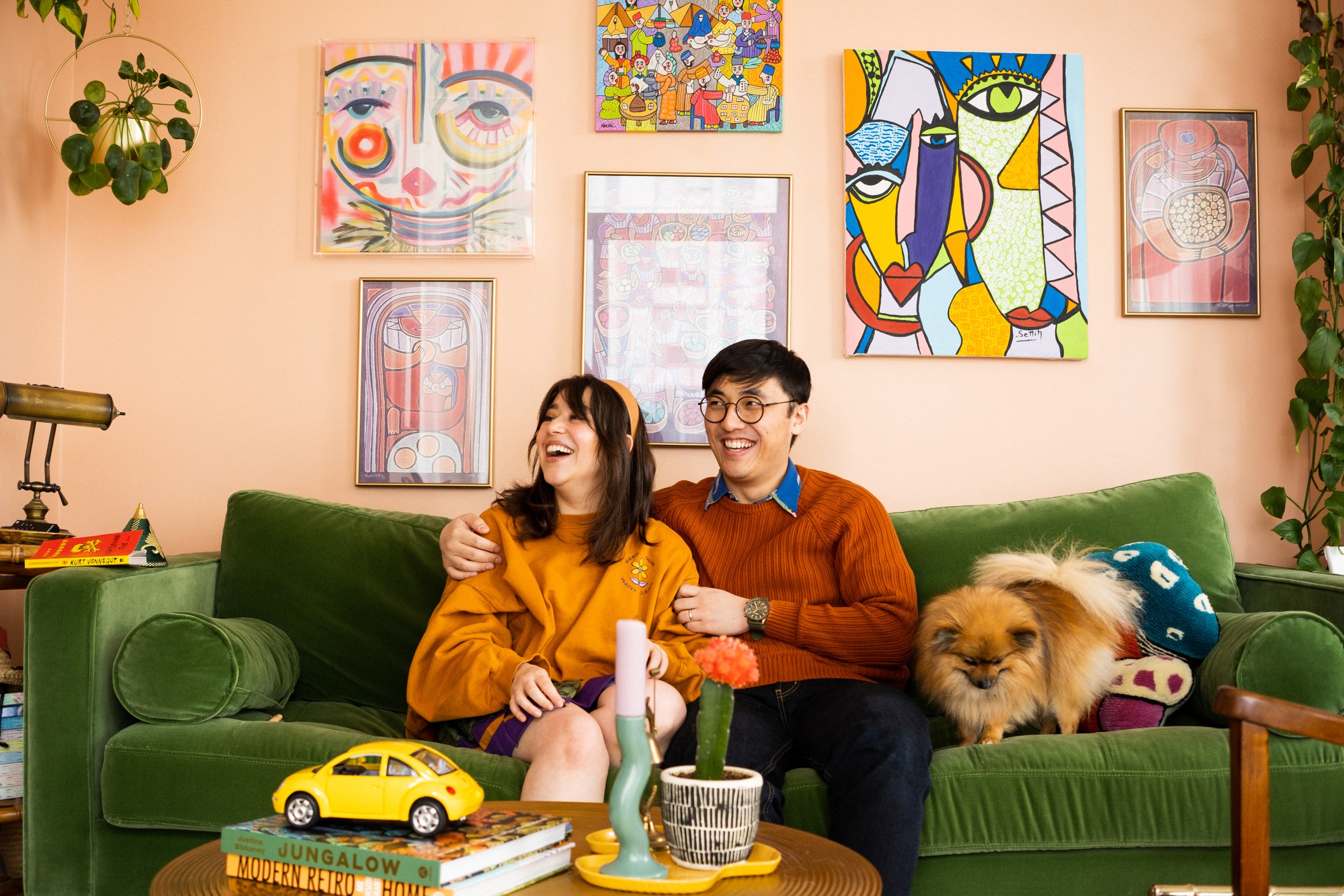 Two Airbnb hosts sitting in this living room on a green couch with their dog.