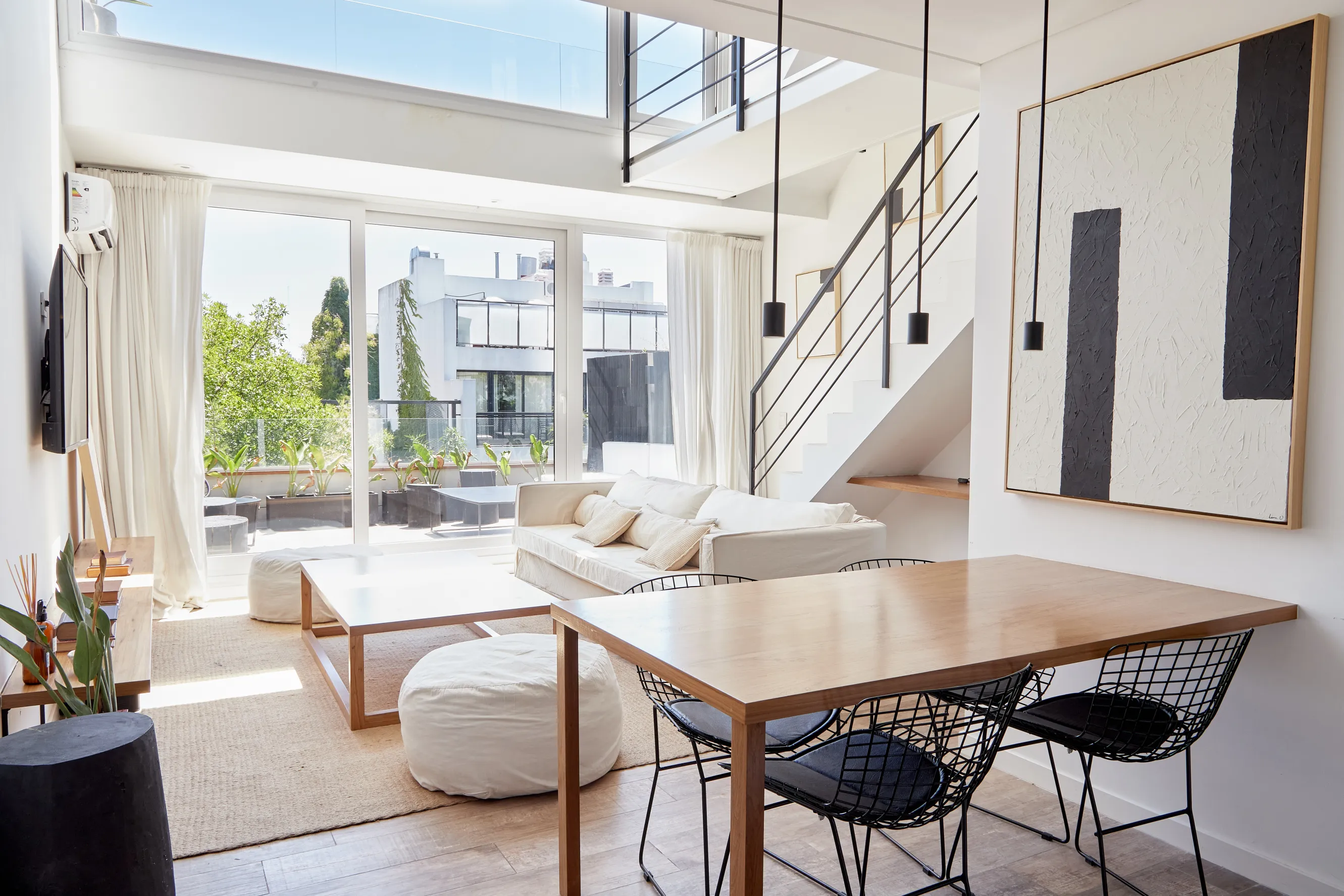 A light, black and white living room with modern art and cozy furniture