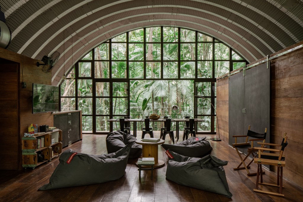 View of tropical rainforest with a living space, wooden villa, and dining area. 