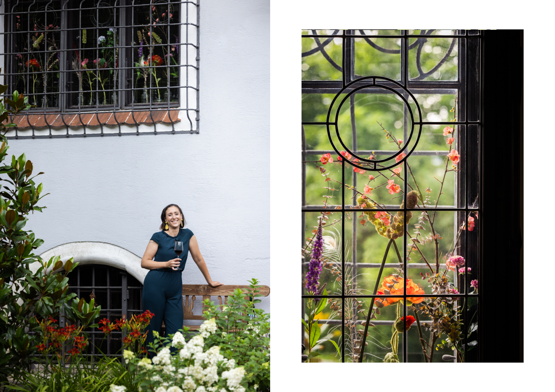 The Host is standing in front of the historical home with flowers in the foreground. 