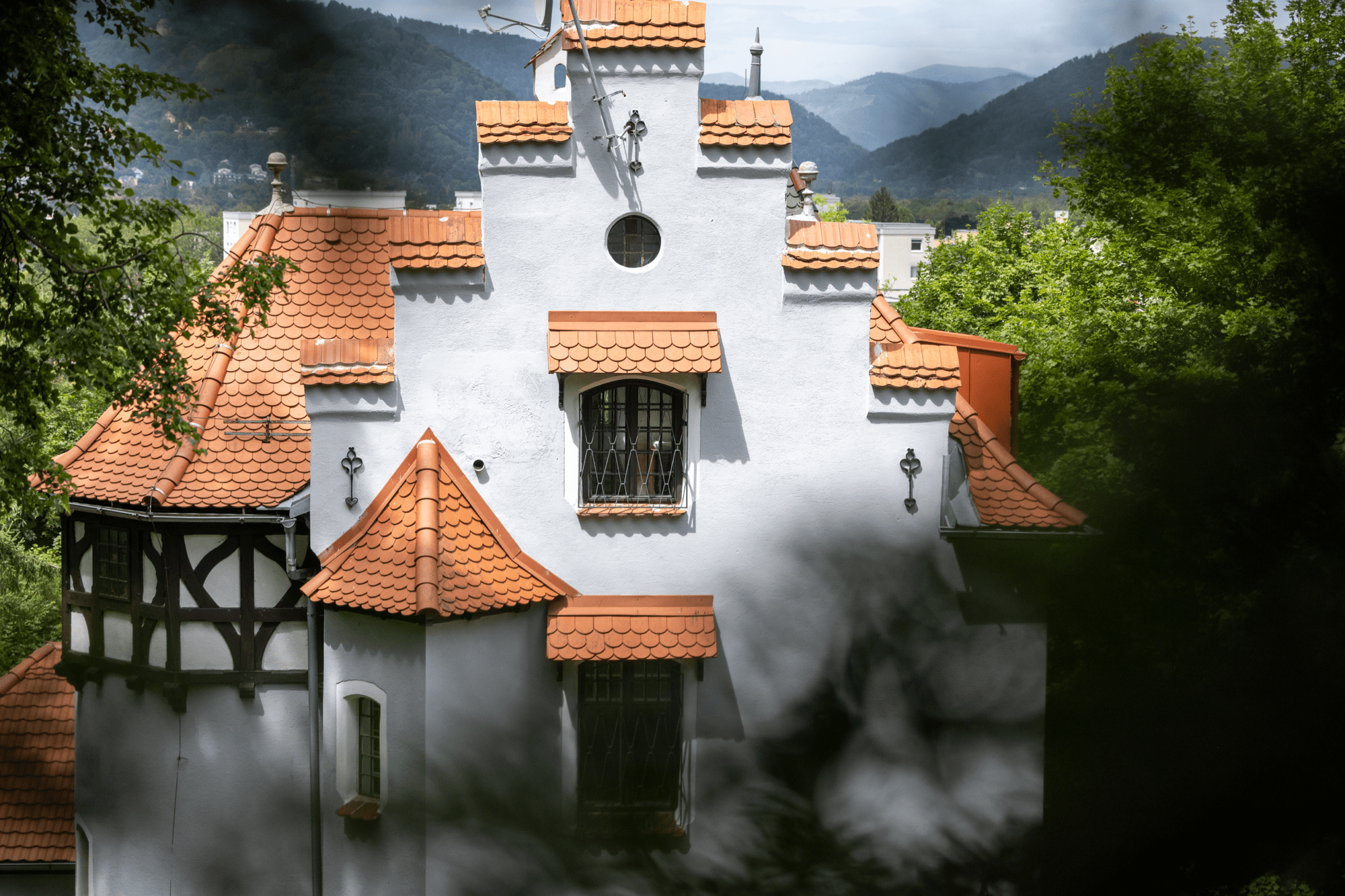 A historical home embedded in a green landscape with mountains. 