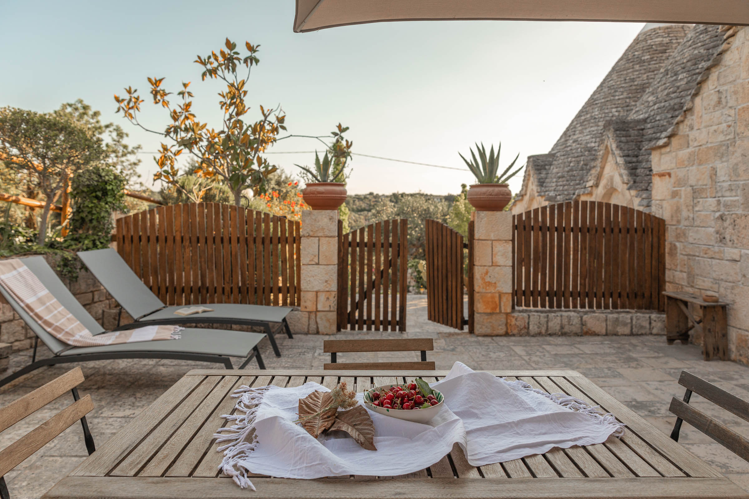 Picture contains a view of a fence, two sun loungers, and a small outdoor area.