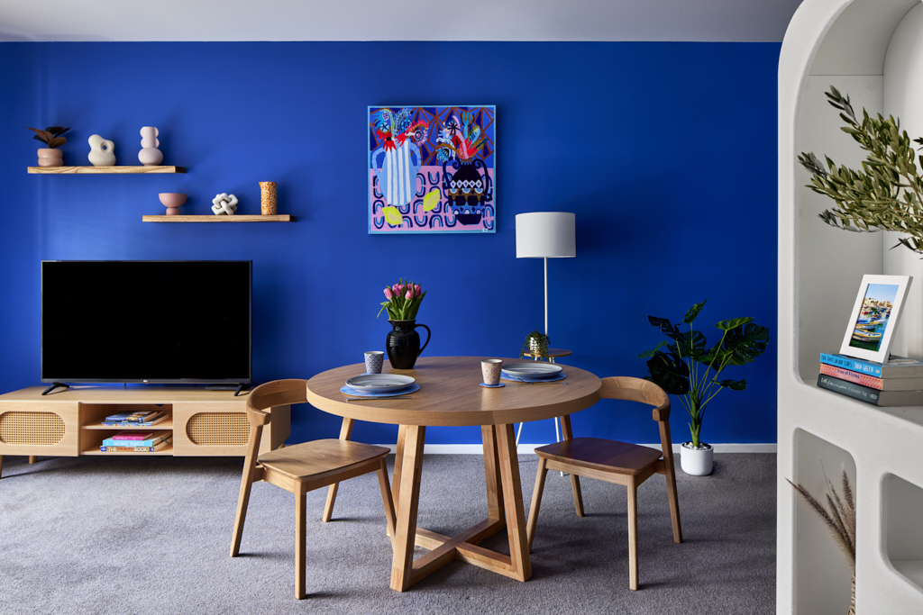 A blue painted living room with a breakfast table and flowers.