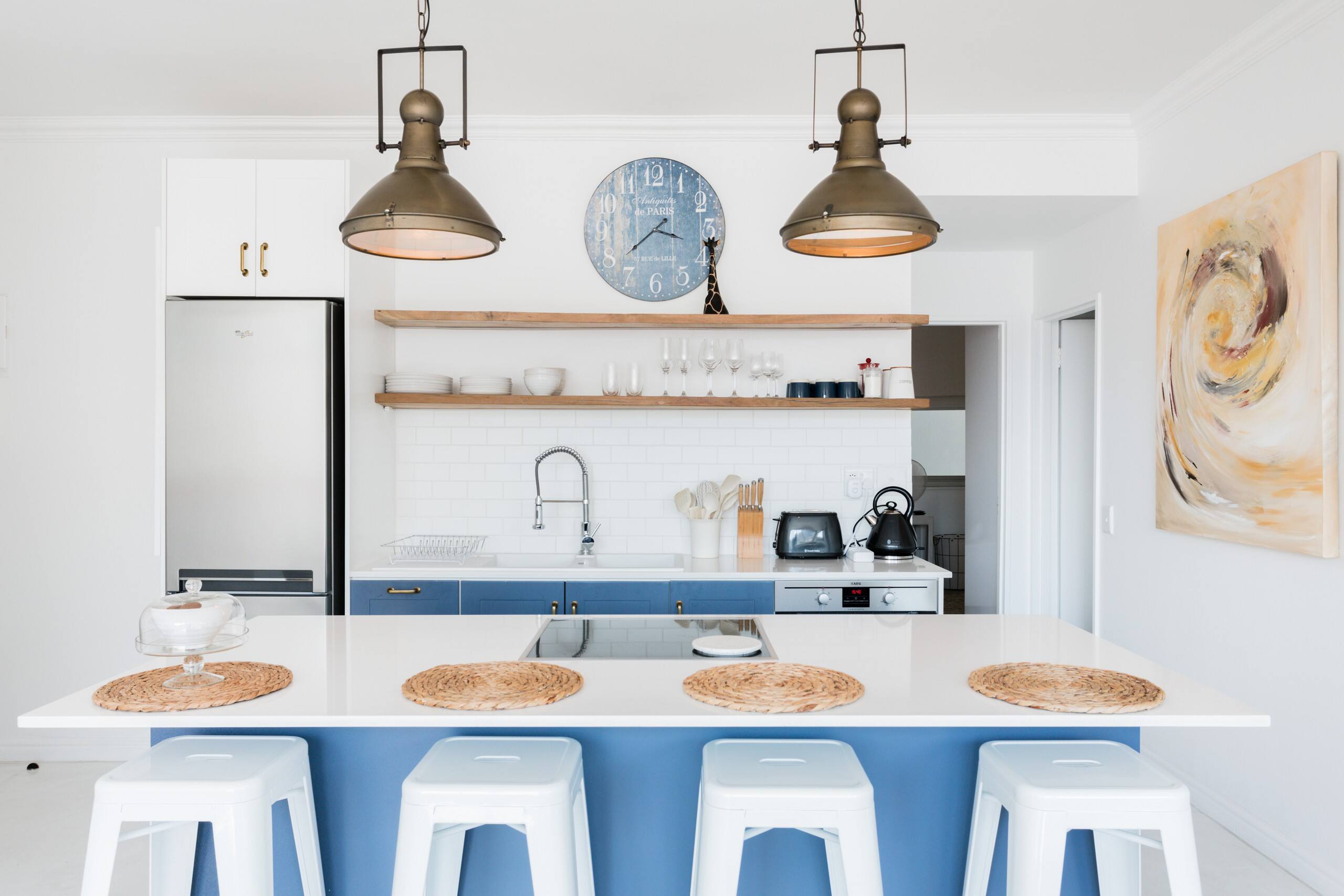 A minimalist kitchen with blue cabinetry and kitchen island siding.