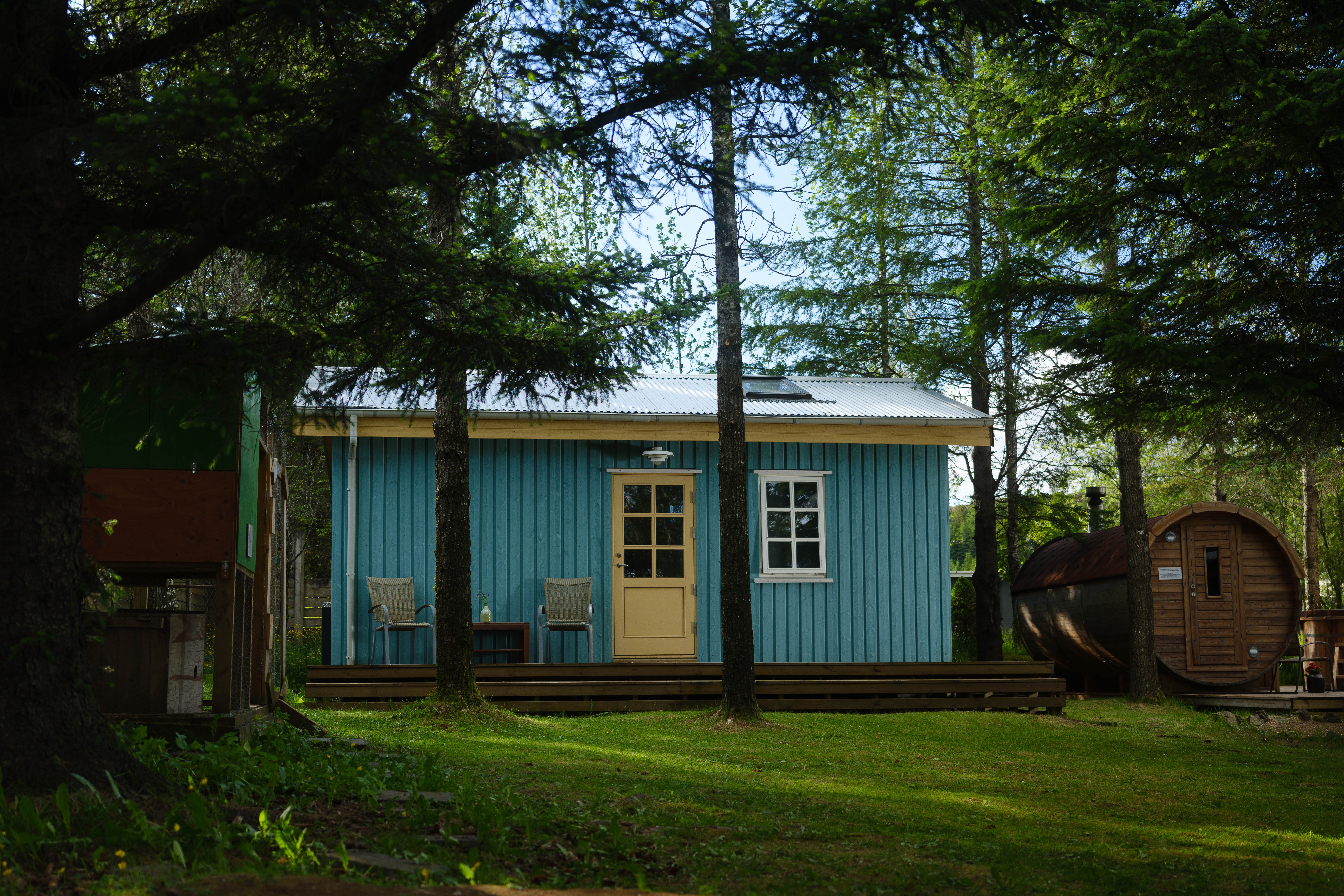 A light blue tiny home with a wood-fired sauna on the side of the house.