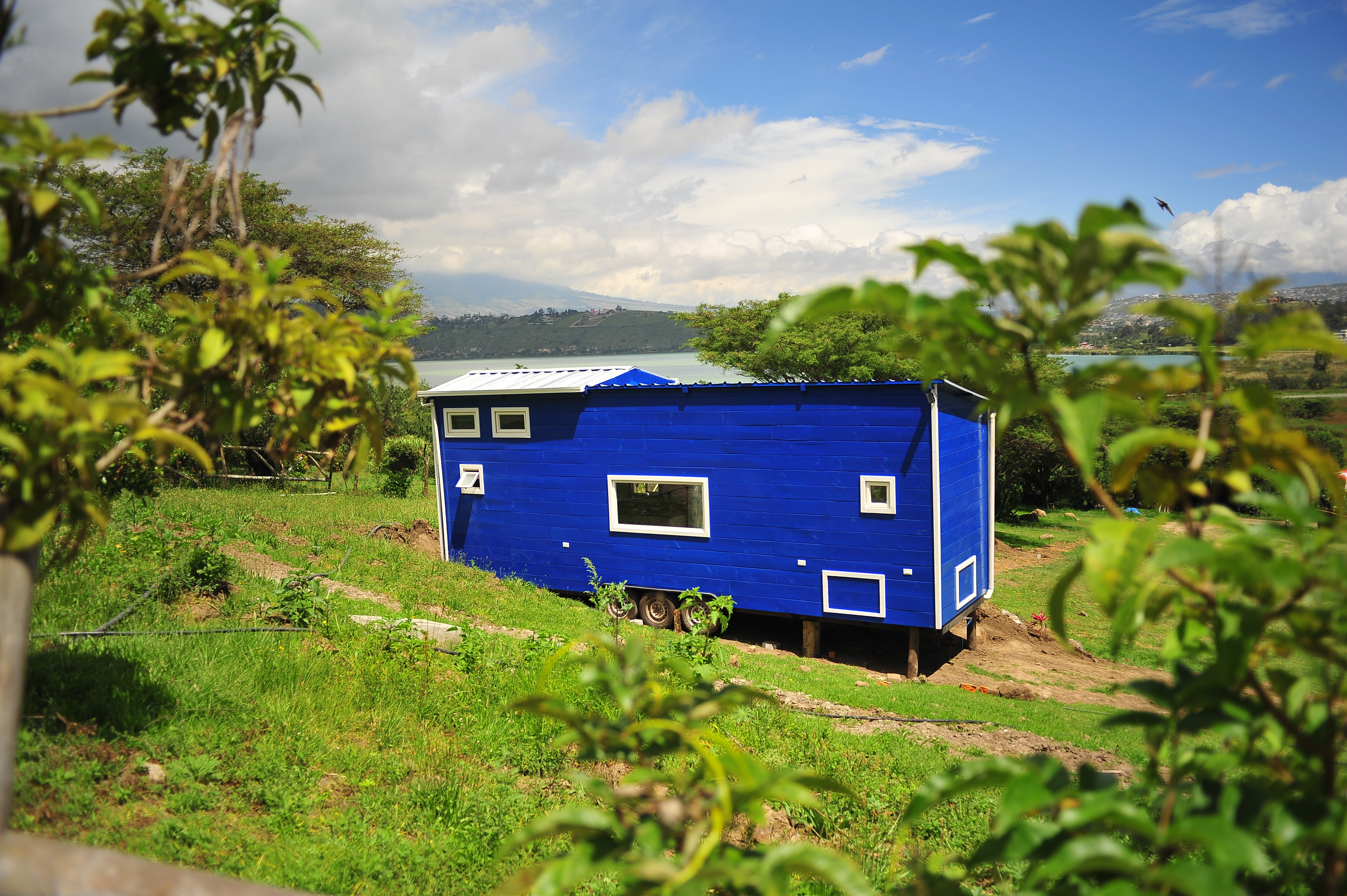 A bright blue finca home with views of the water surrounded by green and lush greenery.