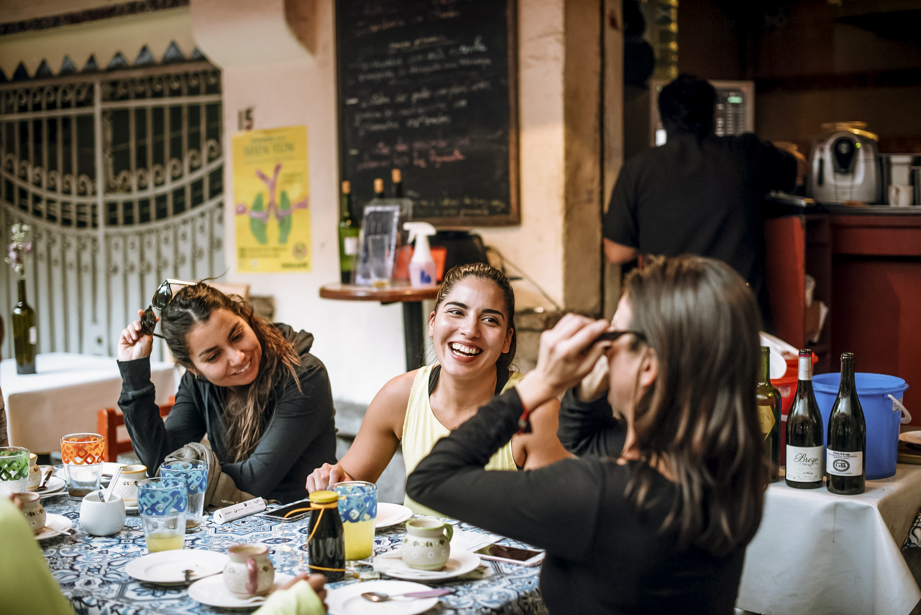 Tres mujeres sonriendo y conversando en una mesa de un restaurante