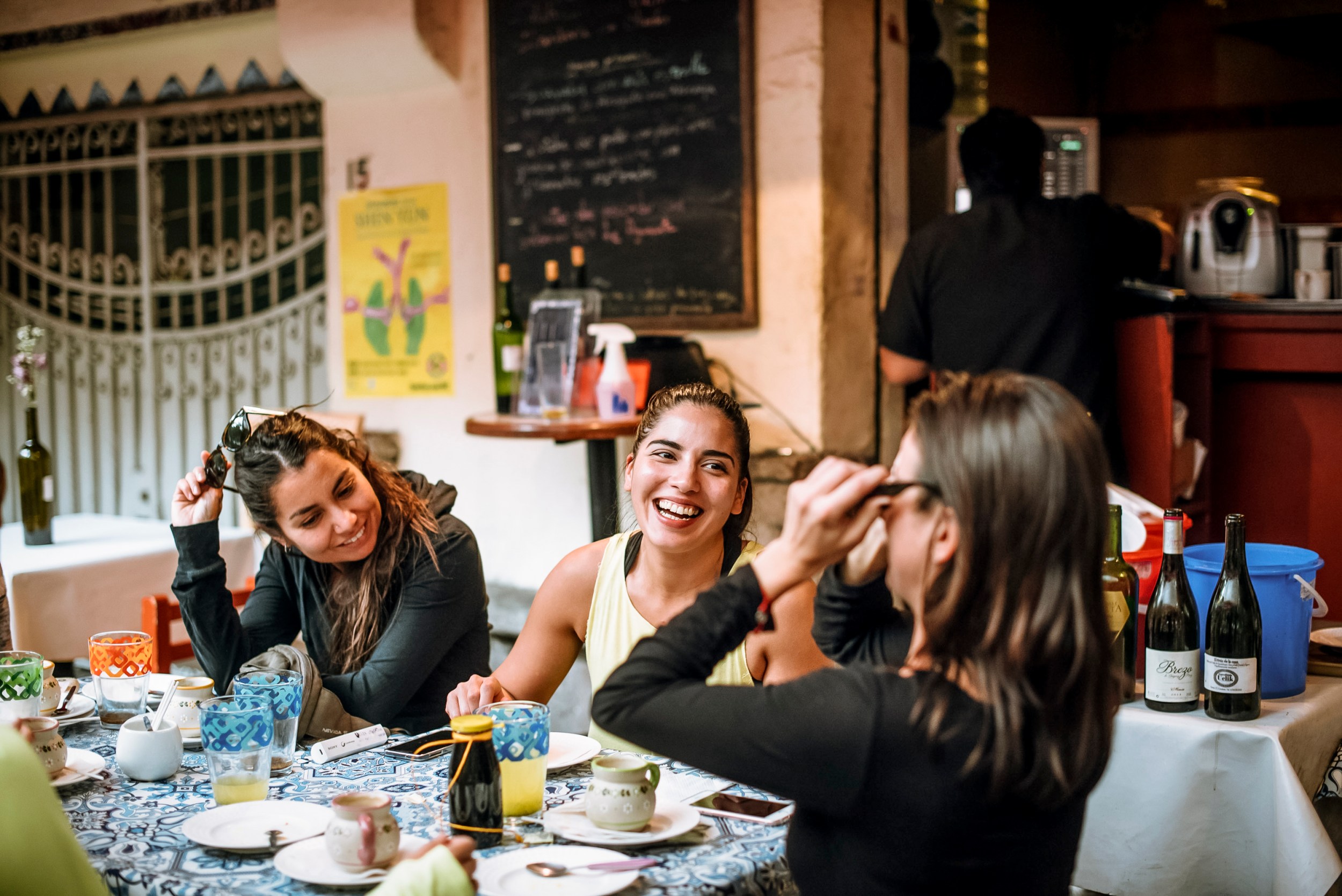 Tres mujeres sonriendo y conversando en una mesa de un restaurante