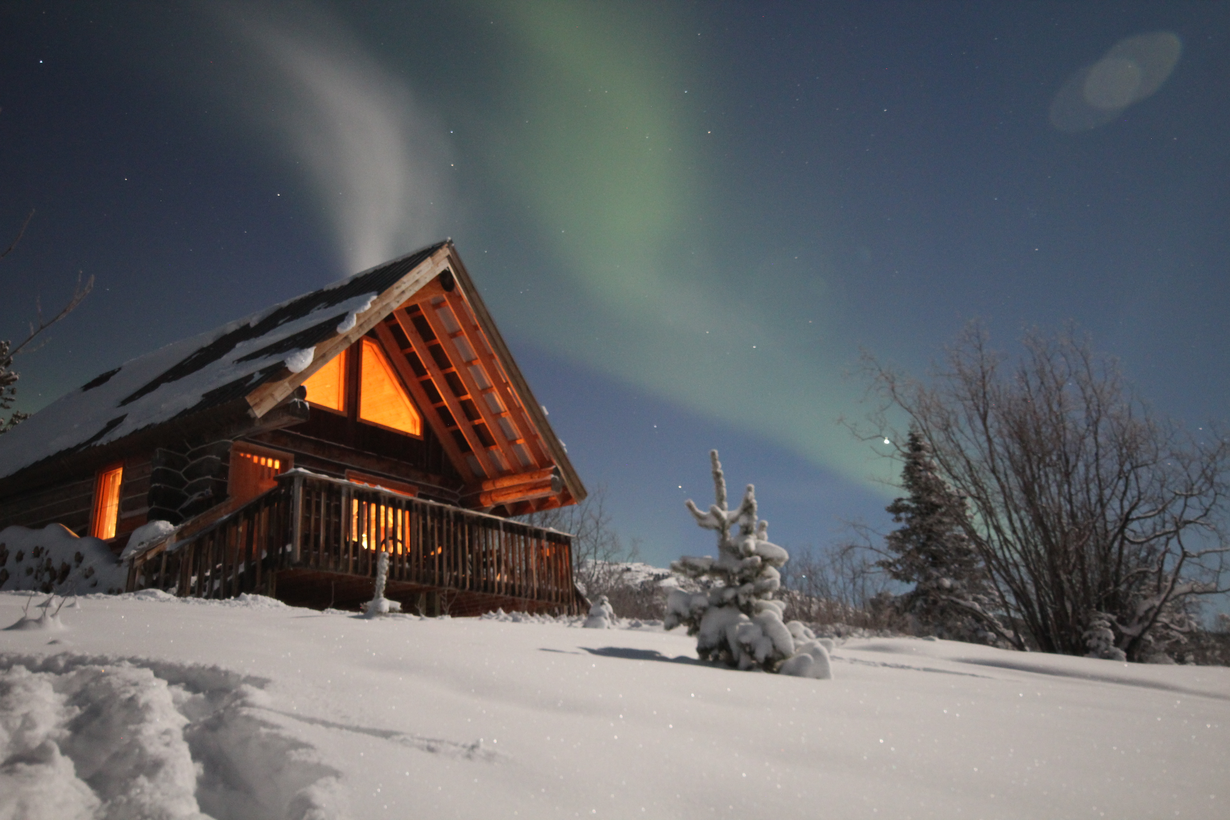 A cabin at nighttime with the northern lights in the sky