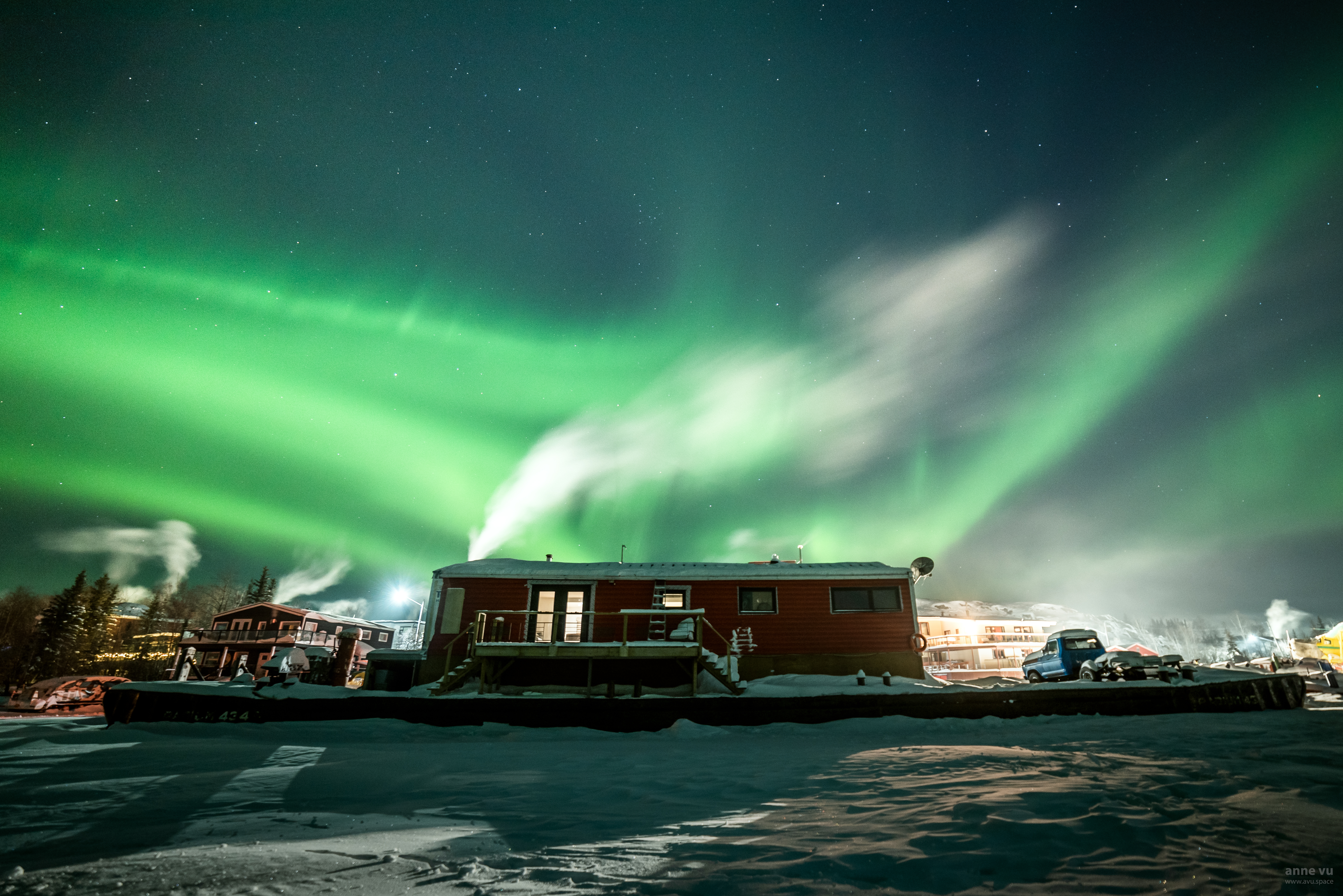a docked houseboat at night with the northern lights above it.