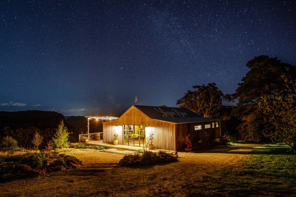 Exterior shot of a timber clad converted machinery shed at night.