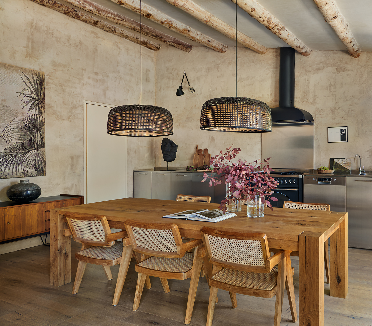 Comedor de madera con seis sillas y dos lamparas de mimbre colgantes encima del centro de la mesa