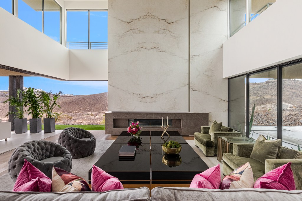Living room with couches and chairs and pink and green accent colors throughout.