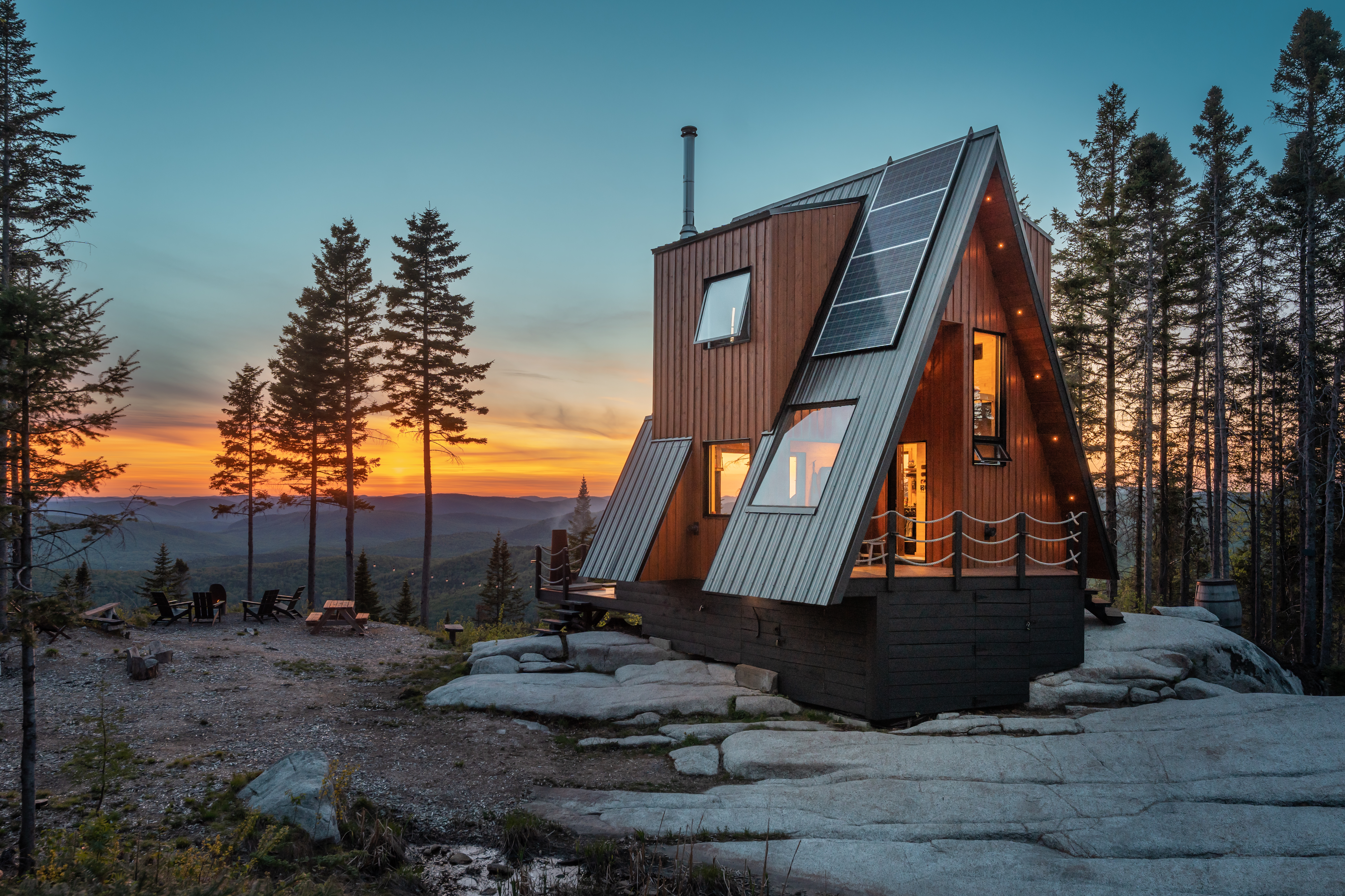 An a-frame cabin in the forest at sunset. 