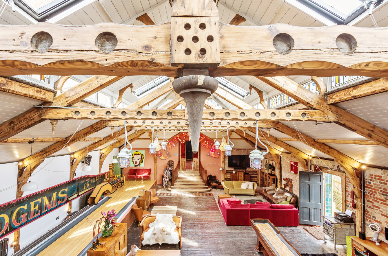 Interior shot of converted Turkish Bathhouse - a large high ceilinged living room with exposed beams and a private bowling alley.