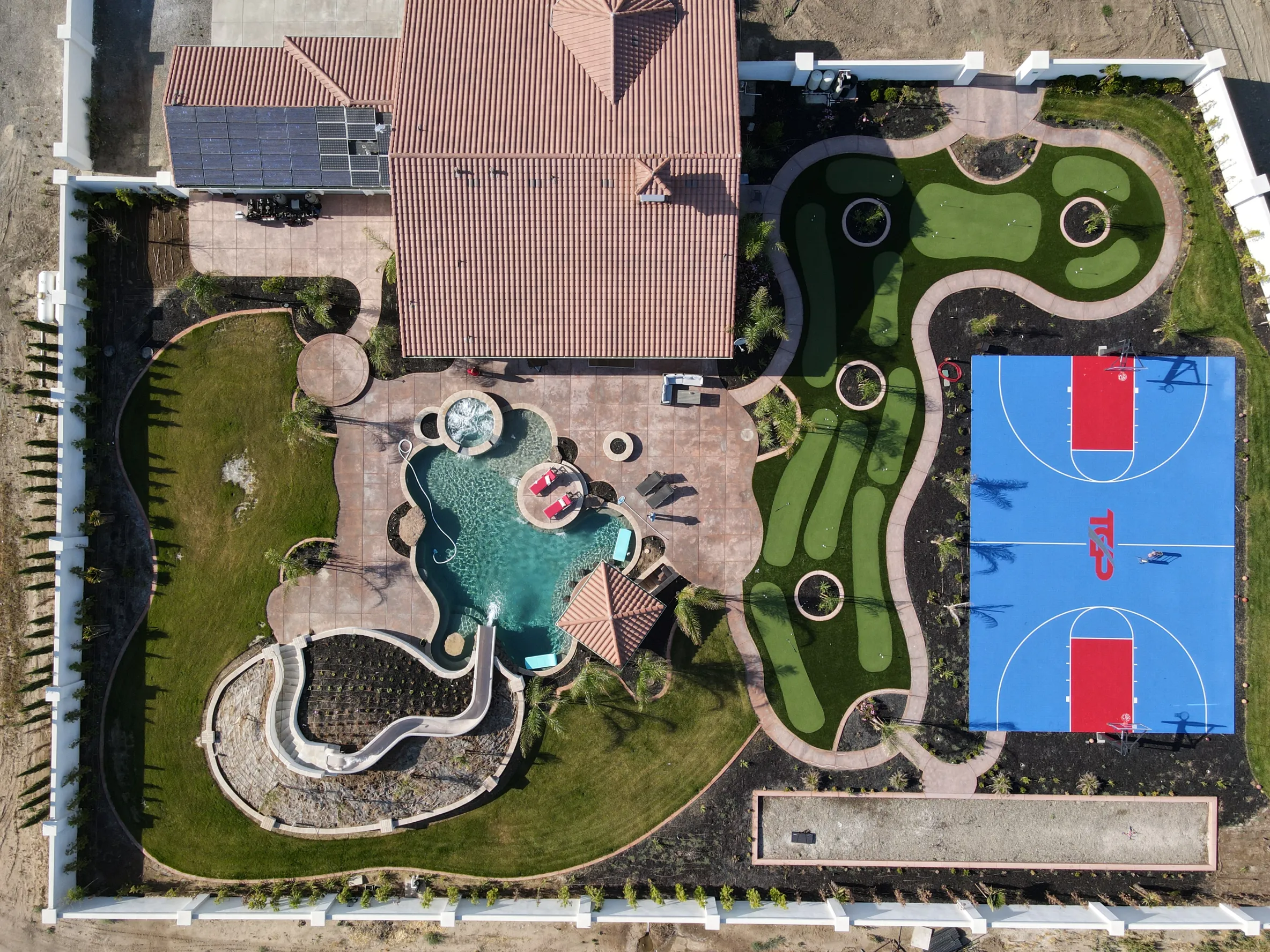 Aerial shot of an 'entertainment oasis': a large home with an expansive garden featuring a tennis court, mini golf course and swimming pool.