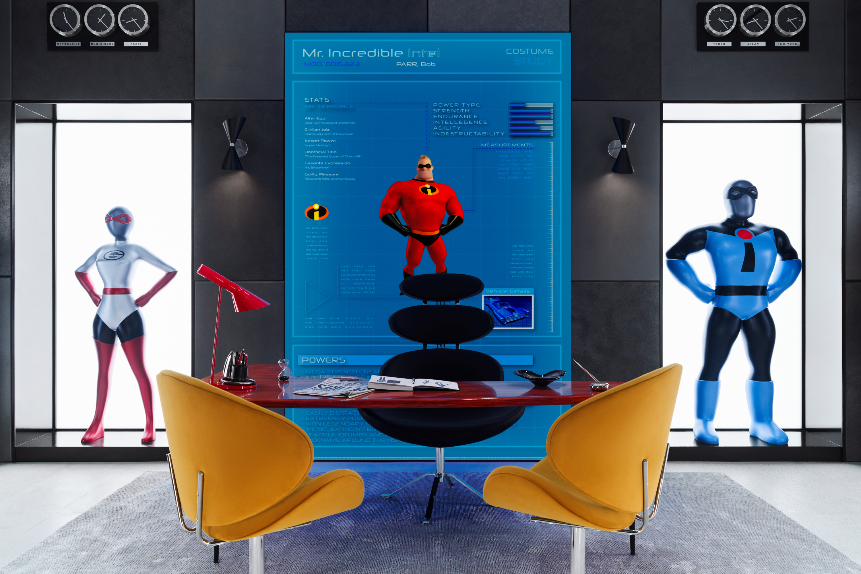 Edna Mode from Incredibles office with two display mannequins on the wall. There is a desk in the middle with the two modern yellow chairs for guests. In the background on the wall there is a large screen showing information about the suit including stats and a photo of Mr. Incredibles in his red and black suit, including his black eye mask