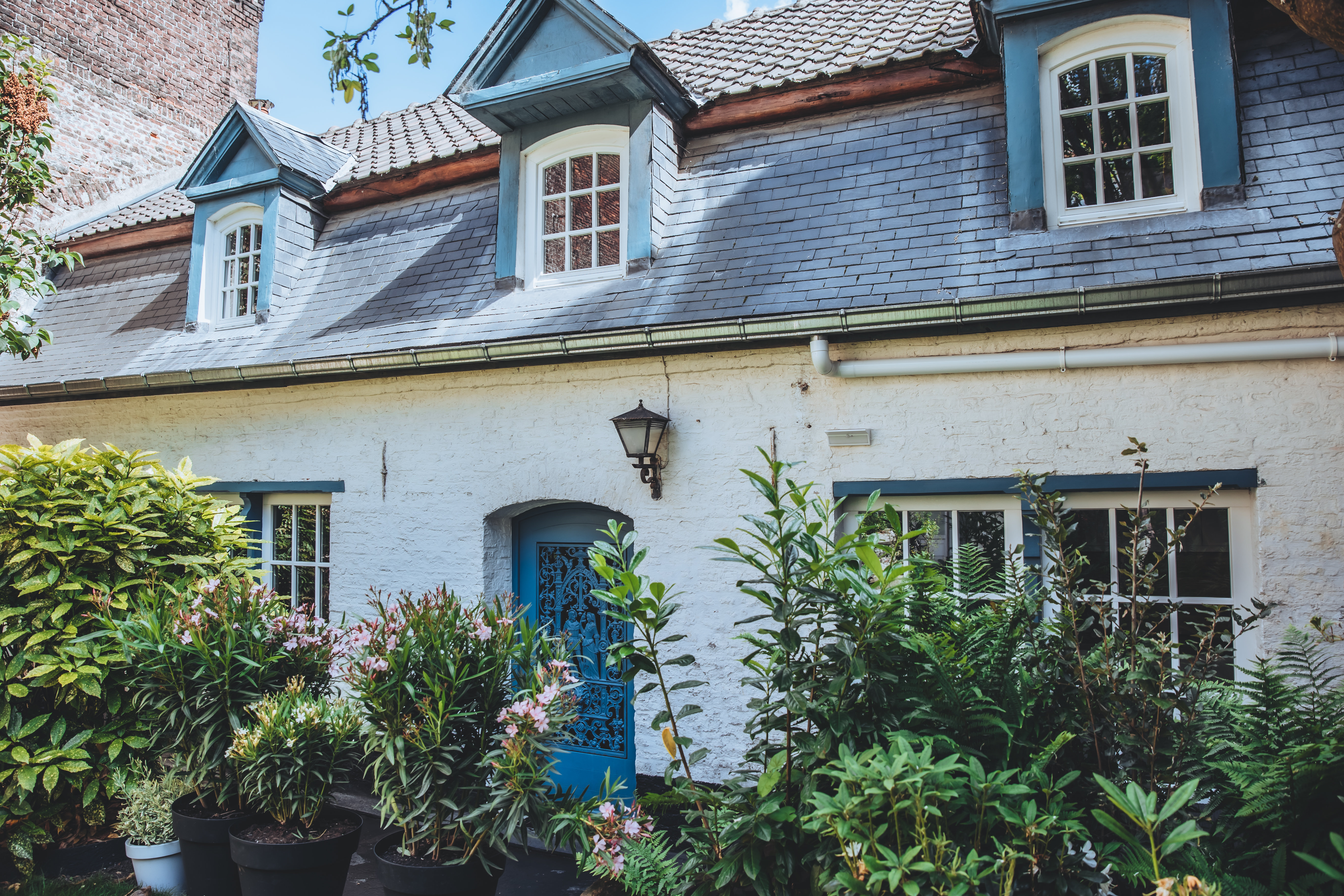 Exterior shot of an historic house in Little. A stone cottage with a mansard roof and dormer windows at attic level.