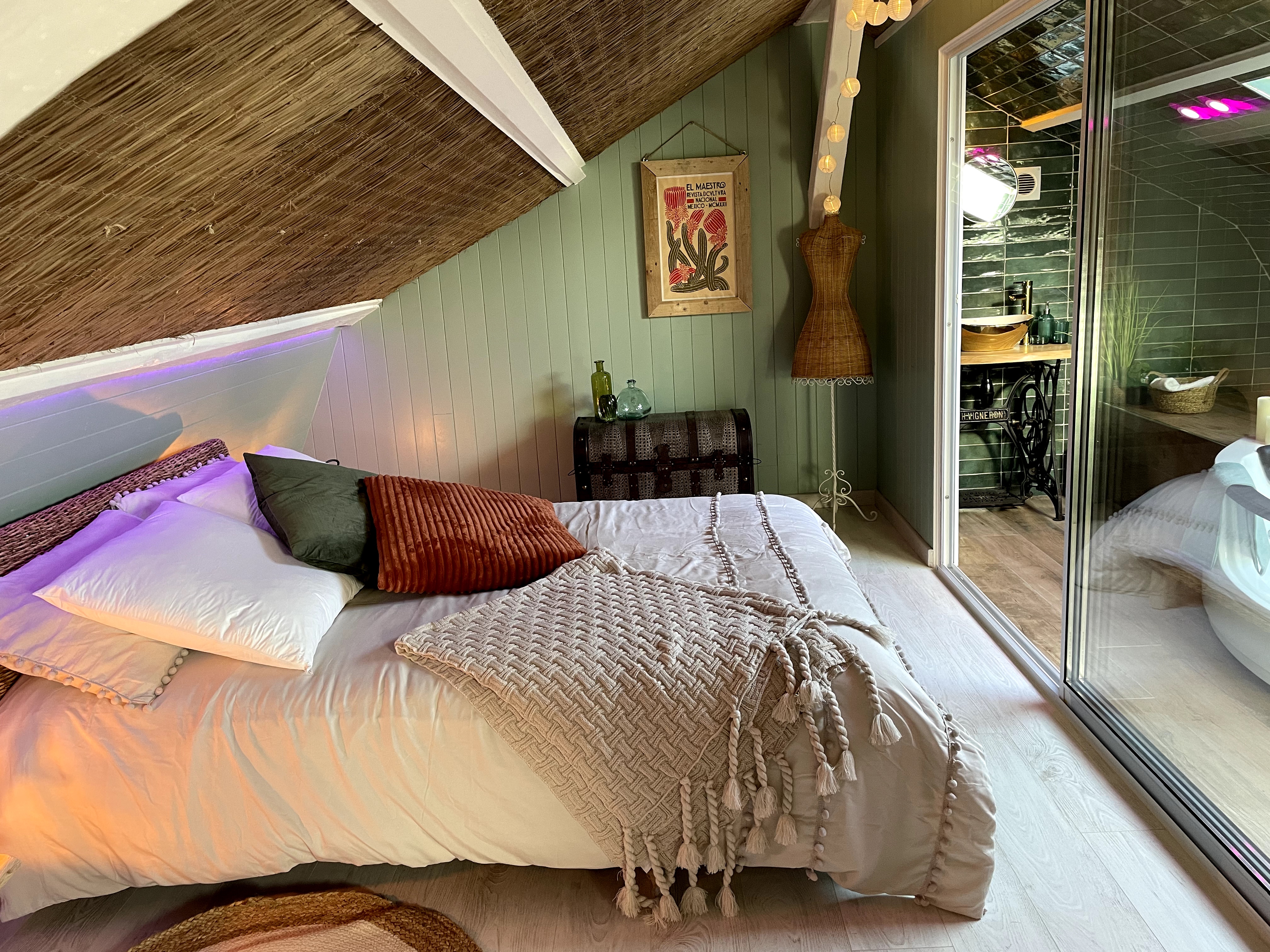 Attic bedroom in an Entire Home in a home located outside Paris. Room features tongue and groove walls painted green and a large bed with a scatter cushions and a woollen throw blanket.