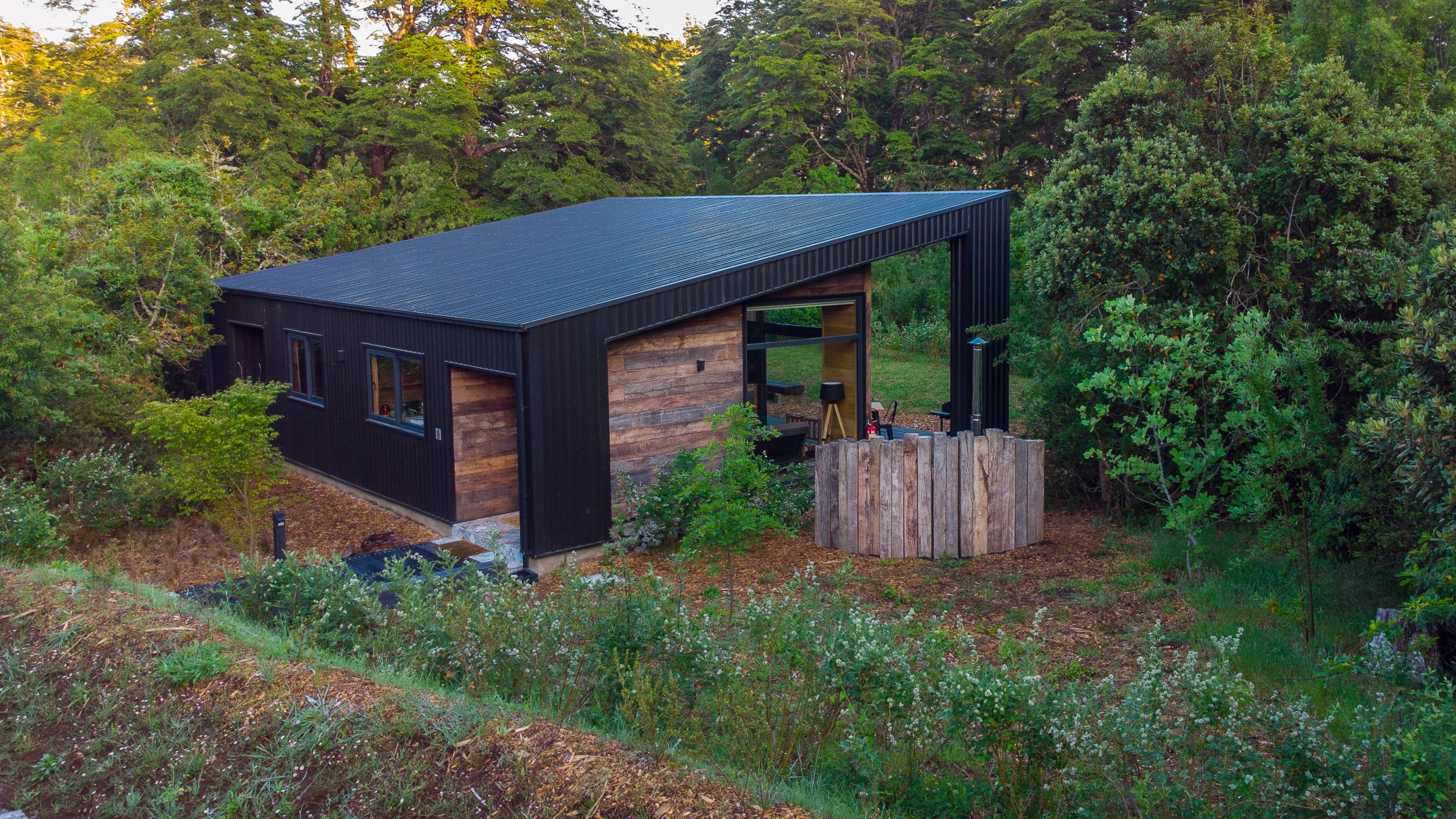 Wide view of a black cabin in the middle of the woods in Pucon, Chile