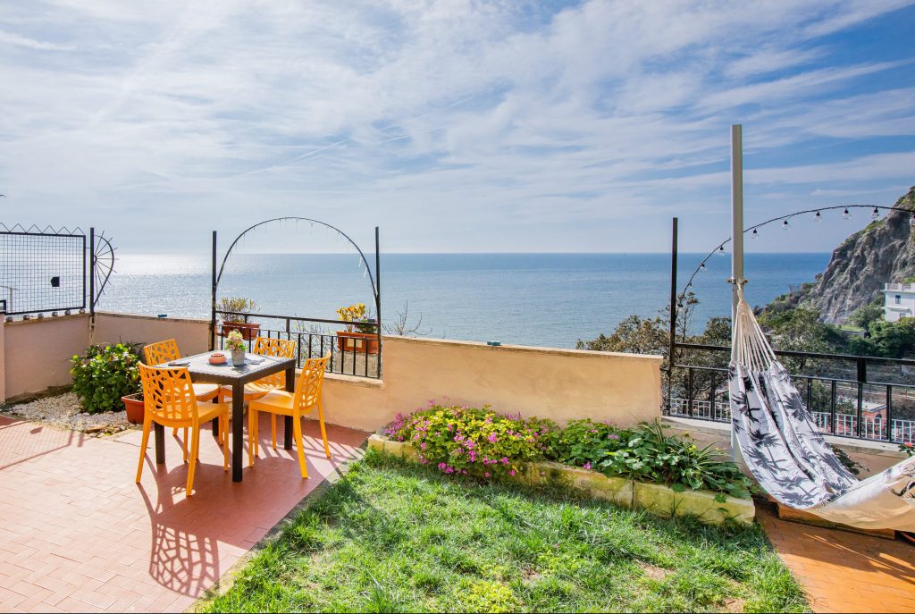 Patio with tables and chairs and a hammock overlooking the sea