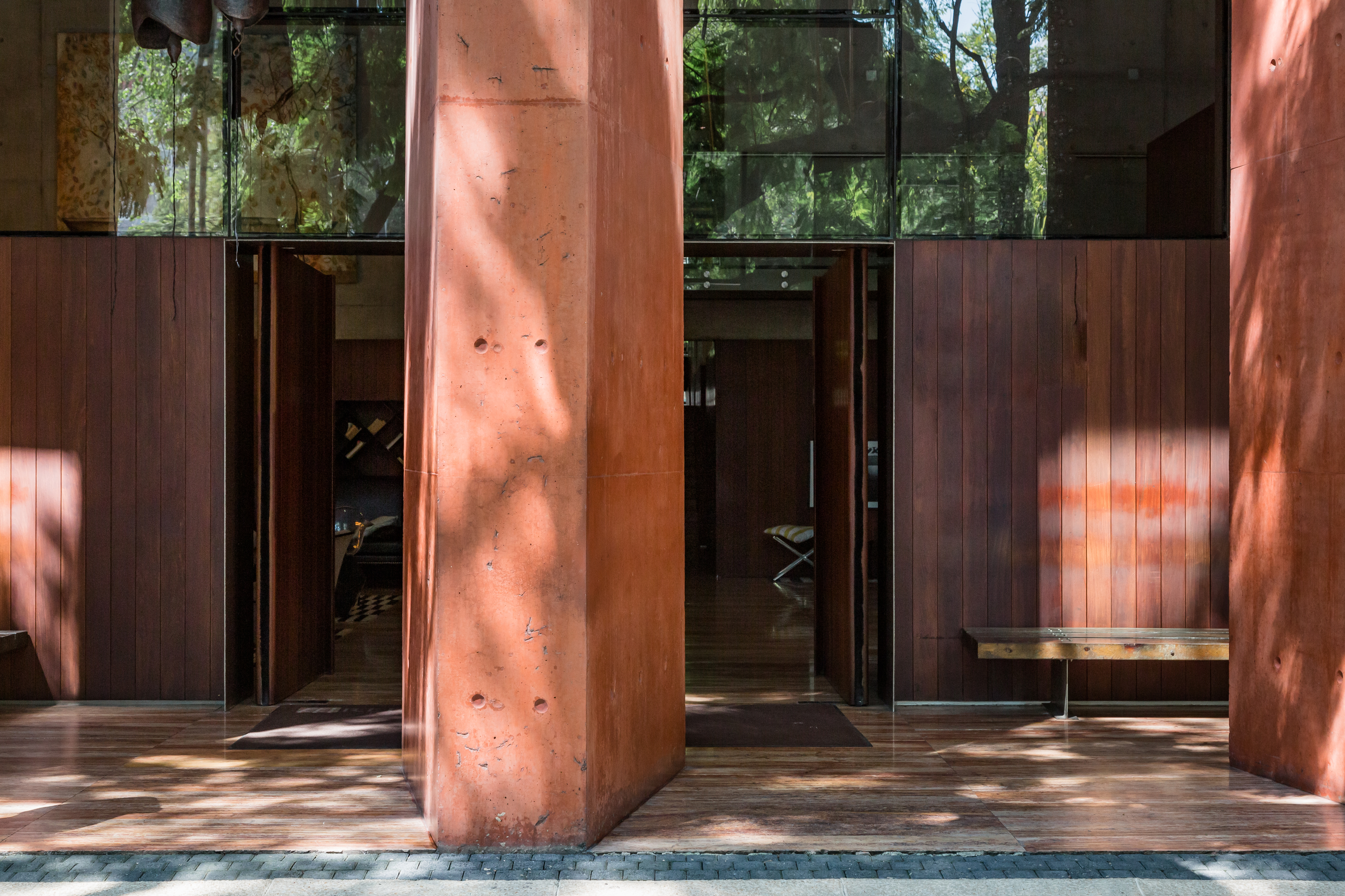 Front door of a listing in Mexico City with a view of a column in the middle, interiors and trees in the backyard