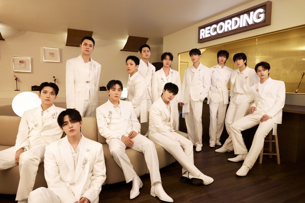 Men in white suits assembled in a recording studio, with a glowing 'Recording' sign in the background.
